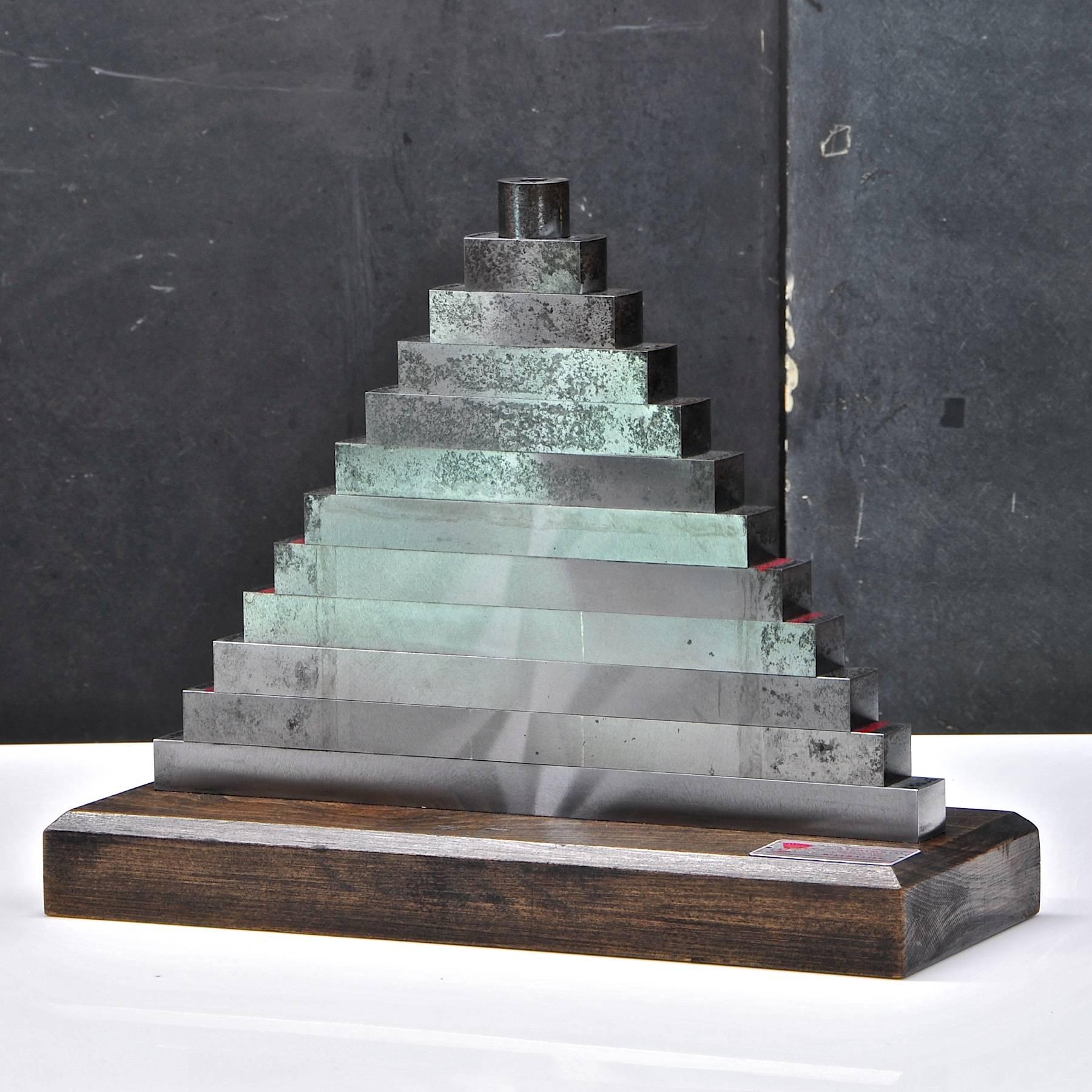 Machinists stacked solid steel measuring device pyramid sculpture. Some oxidation stains to the steel, no dents or impact damages. On a black wooden base. Very heavy.

Measures: W 13¼ x D 5 x H 10½ in.