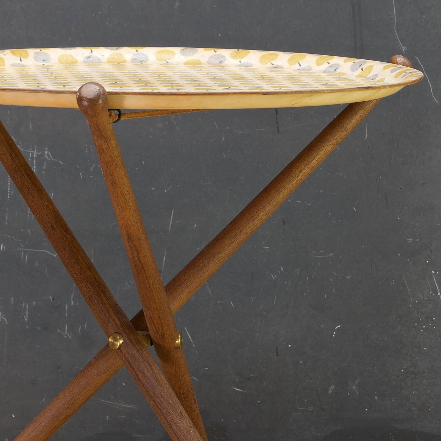 Nils Trautner Dreibein-Tischgestelle aus Teakholz, kombiniert mit einem in Schweden hergestellten Tablett mit buntem Apfelmuster, entworfen von Astrid Sampe. 

Maße: Dia 17 3/8 x H 17 3/8 in.