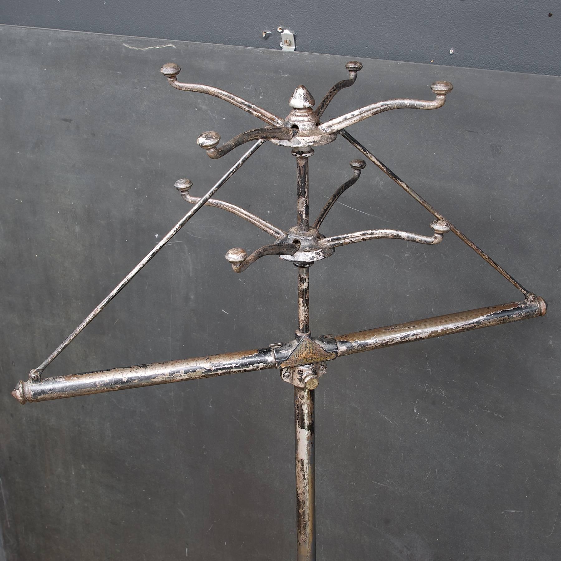 USA, circa 1890s. Vintage Industrial bonneville power plant office folding coat rack. Fully functional and complete. Cast iron, steel and brass, enameled. Time worn patina, and metal inventory tag. Folds out to hang eight garments.

Dia: 26½ x H: