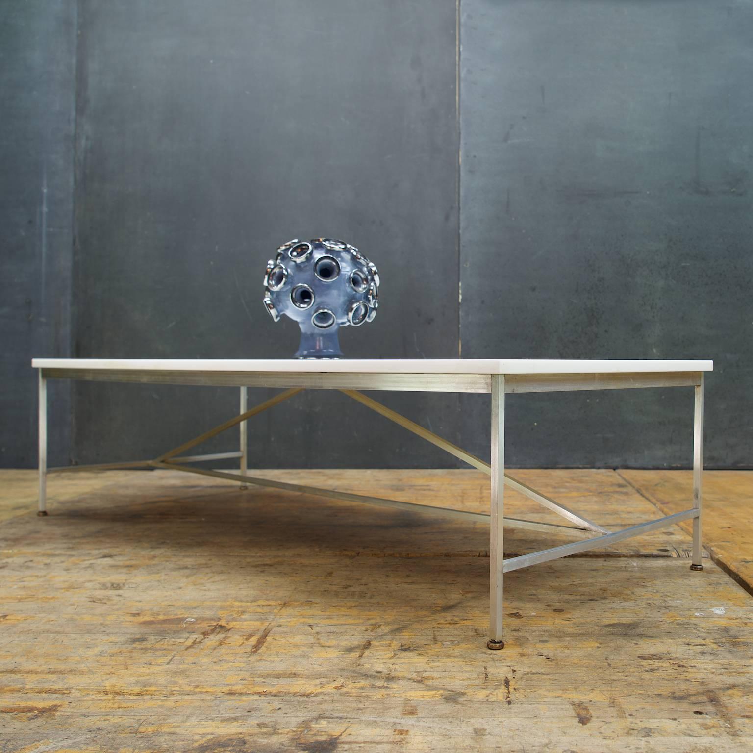 Rare table from McCobb's Irwin Collection by Calvin Grand Rapids. In a satin aluminum frame with triangular stringer, opaque milk glass (vitrolite) surface. A matching McCobb Custom Craft Sofa is also available.