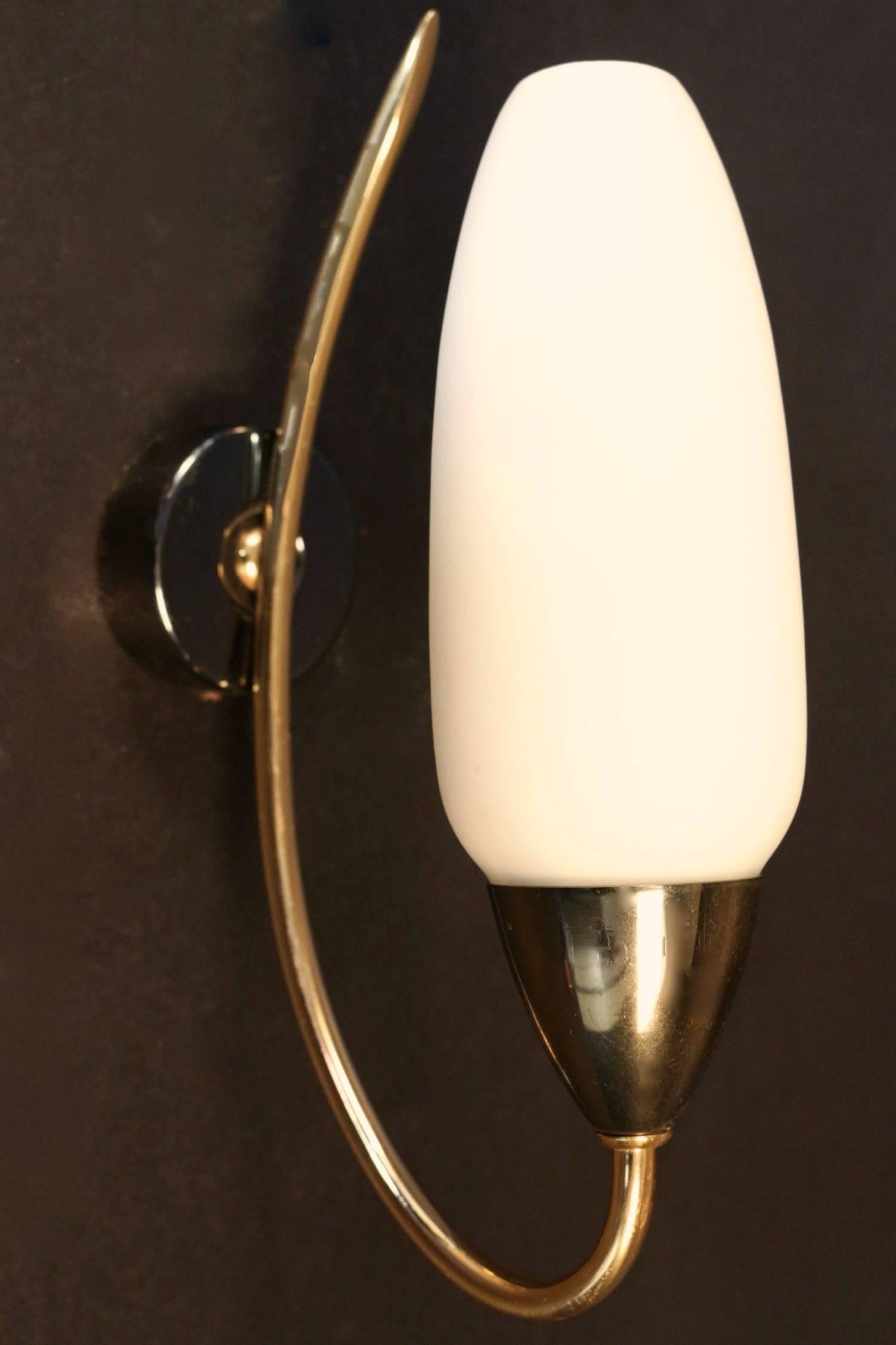 Pair of 1950s sconces by Maison Arlus.

composed of a comma shape brass rod on which stands an ovoid opaline underlined on its base with a grey brown brass border. One lighted arm per sconce.