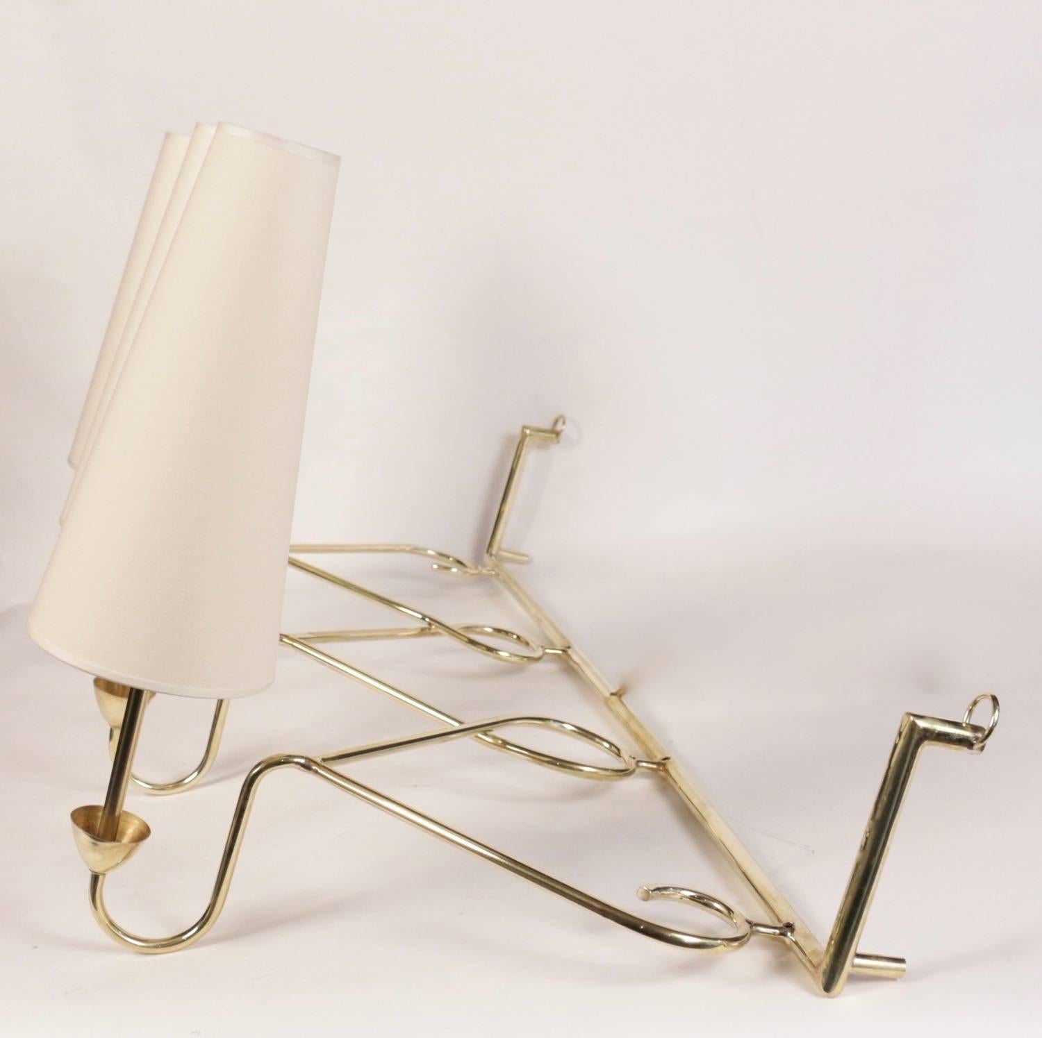 Large 1950s sconce attributed to House Stilnovo.

Nice curved brass work. Each sconce's base underlined with a brass cup.
Three lighted arms surmounted by custom lampshades.