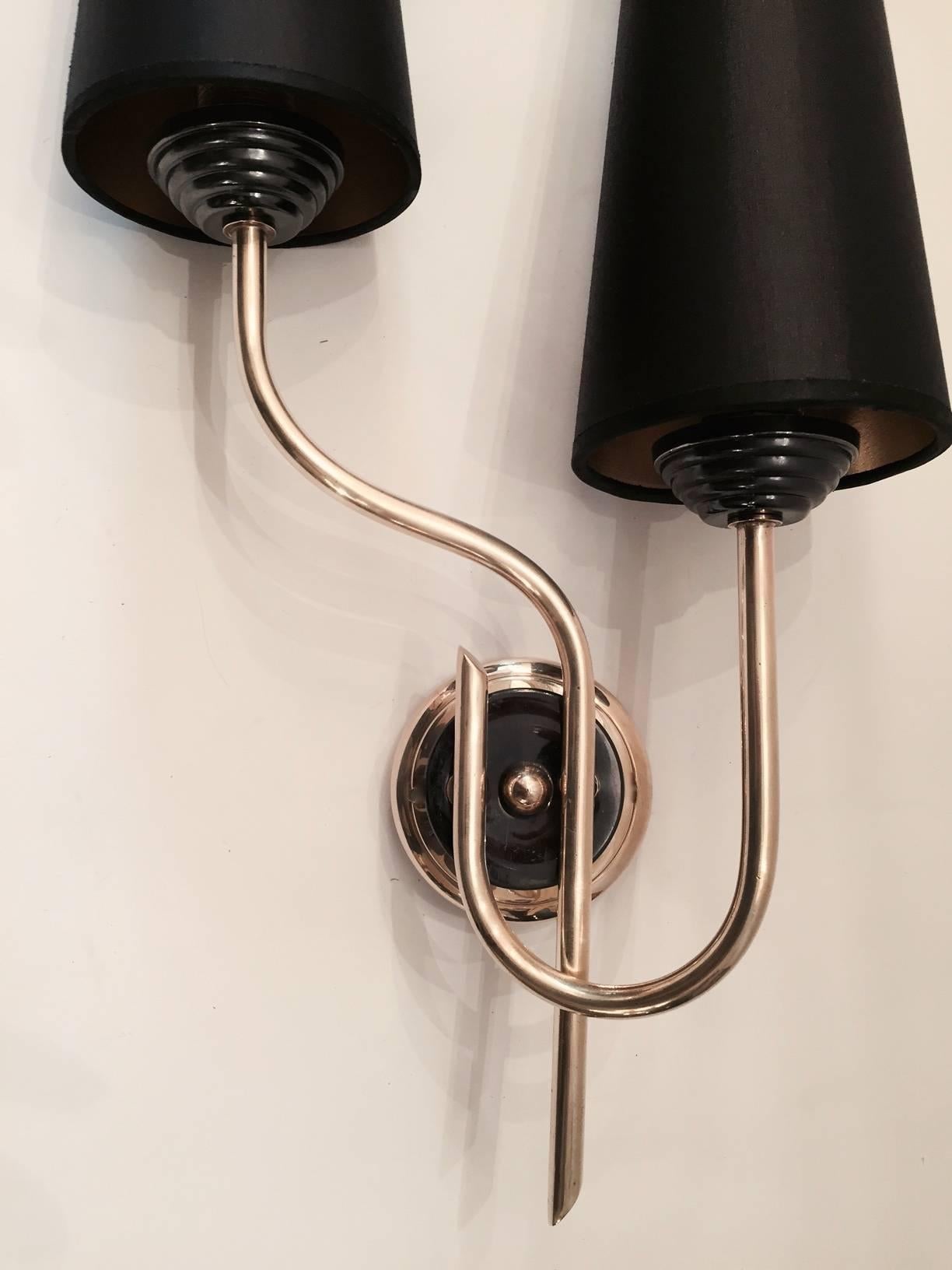 Pair of large 1950s asymmetrical sconces by Maison Lunel.
Composed of two nicely curved and departed gilt brass rods underlined with two gunmetal color brass cups on the base. They are surmounted by custom lampshades with gold color inside and