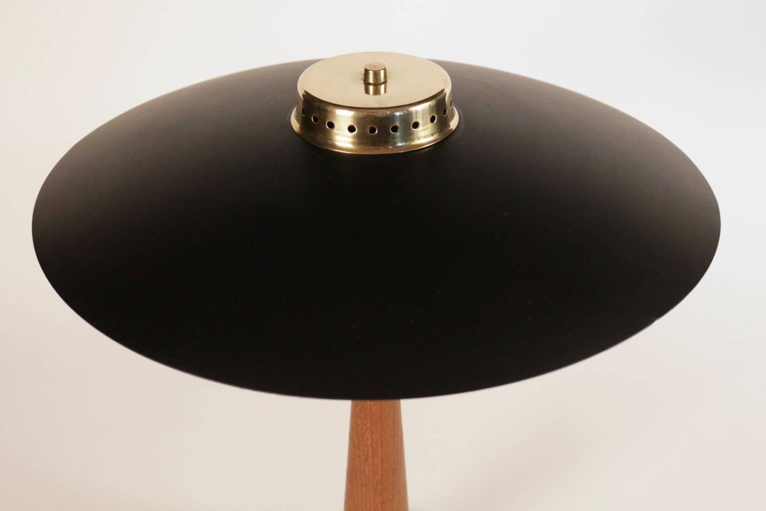 1950s elegant table lamp by Maison Stilnovo referenced on catalog.

Danish Scandinavian style, Stilnovo Edition, Italy.

The weighted brass base has an integrated switch and a solid wood conical pedestal. The lampshade is made of black lacquered