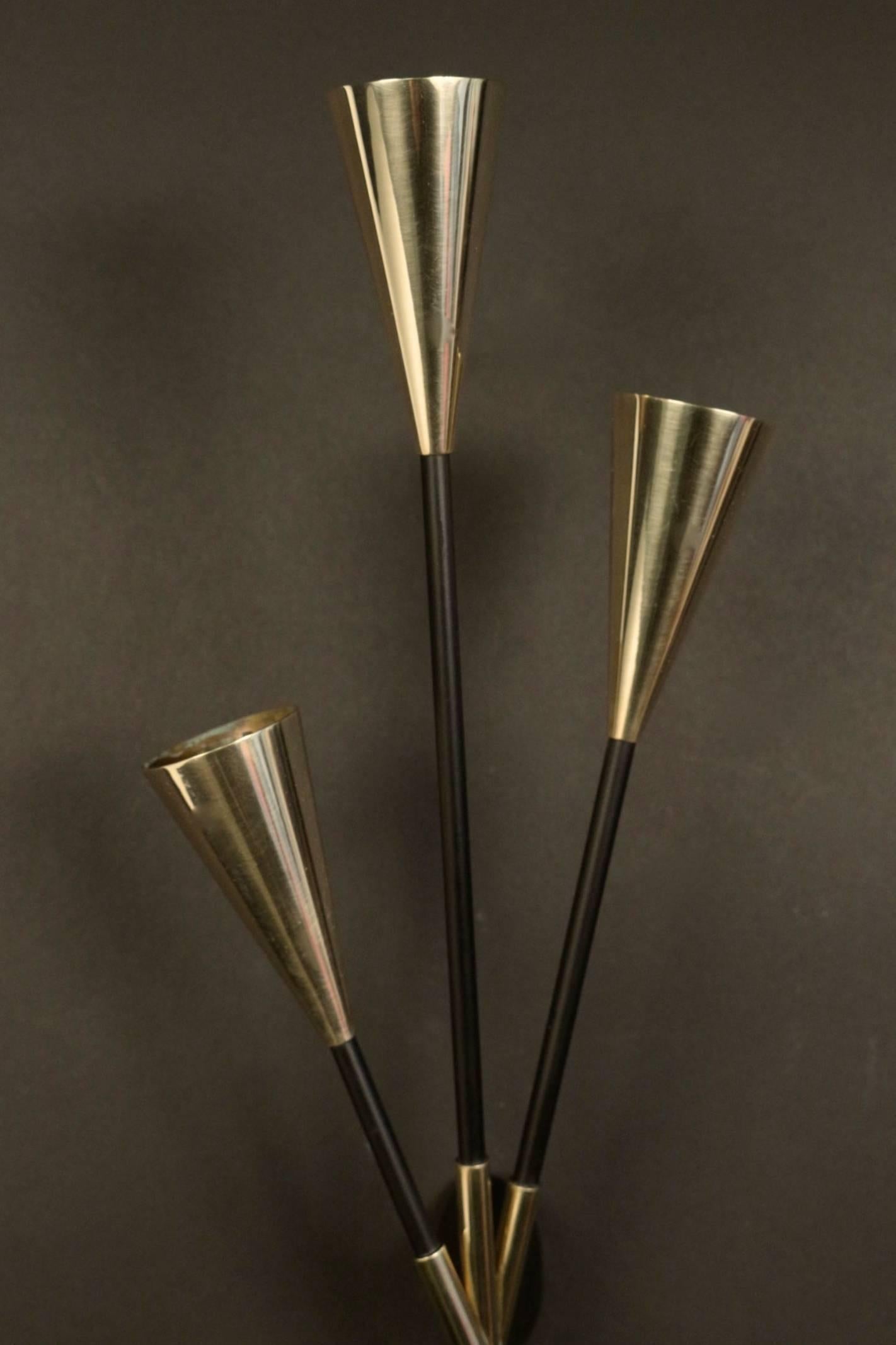 Large pair of 1960s bouquet sconces by Maison Lunel.
Composed of three blackened brass rods set as a bouquet and underlined by gilt brass surmounted by conical gilt brass bulb caches suggesting the flower.
Three lighted arms per sconce.