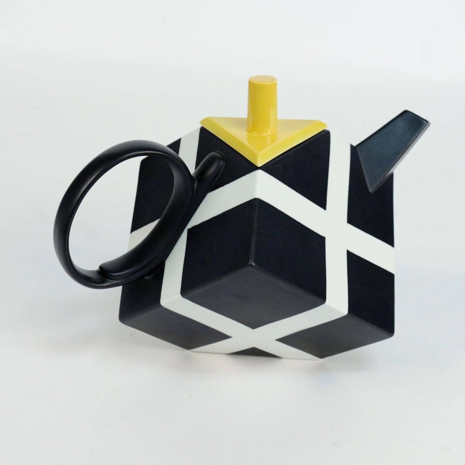 Porcelain tea pot by Rolf Sinnemark for Rörstrand manufacturer. 

Porcelain tea pot and lid with geometric decoration in black and white.
The yellow tea pot cover consists of a cylindrical knob on a flat triangular lid.
Single handle and upward