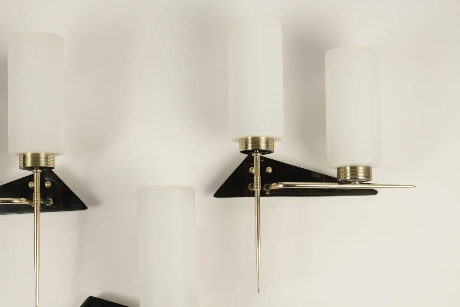 Set of three asymmetrical sconces, Maison Arlus, 1960.

The set is composed by a pair of double sconces and one simple sconce.

Each sconce consists of a triangular shaped backplate made of black lacquer, decorated with brass balls.
The arms