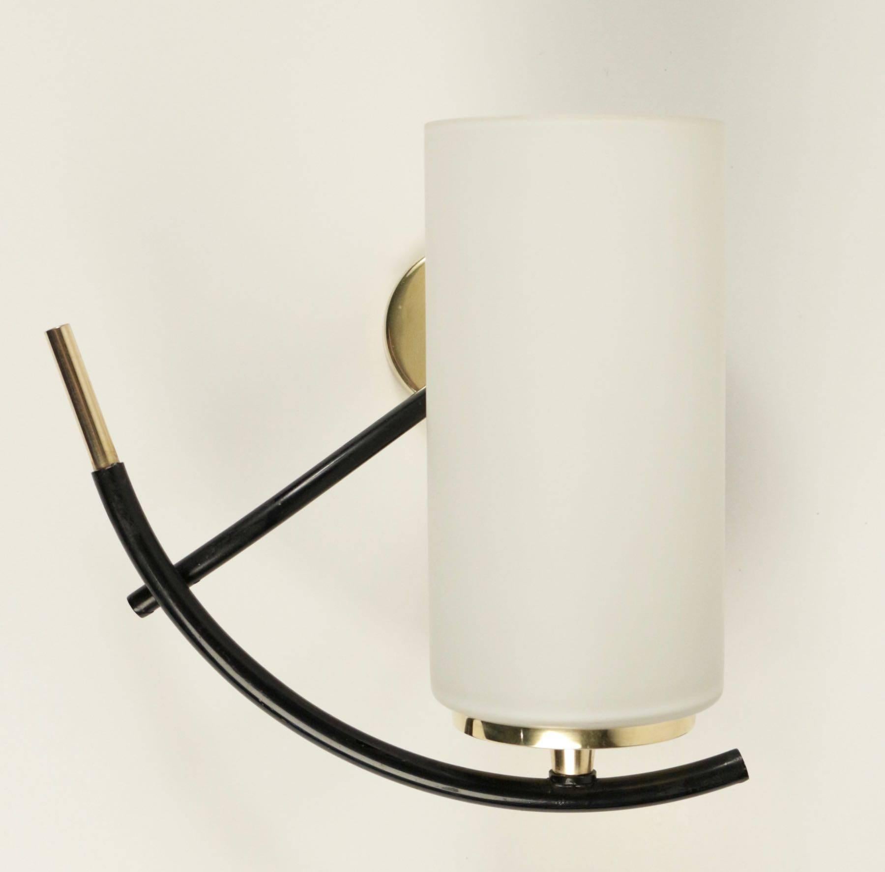 Pair of sconce by Maison Arlus, 1950.

The pair of sconce is composed by two cylindrical opaline glass lampshades mounted on curved black lacquered arm, ended by a brass rod. Round backplate made of brass.
      