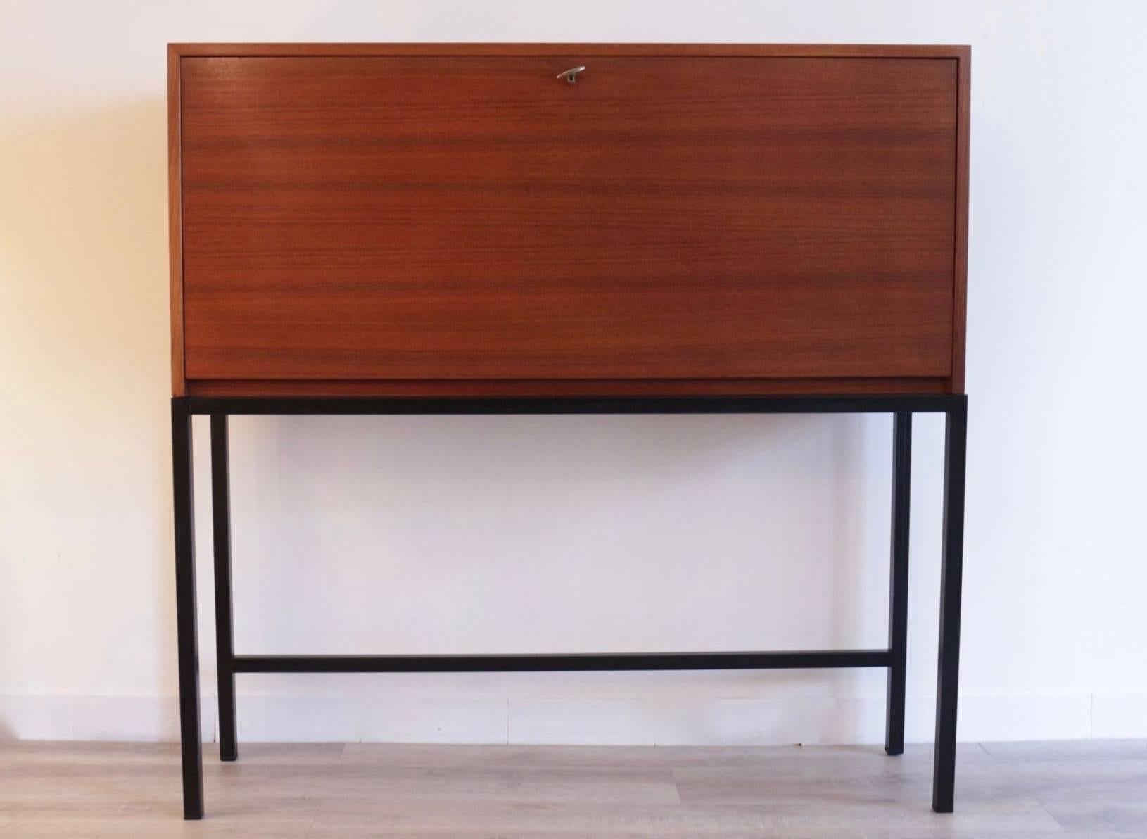 1950 drop front Secretary desk in teak by Børge Mogensen. 

When the front door drops, four storage are revealed. 
The base is composed by four black lacquered steel legs. 
Door lock and key made of brass. 
Børge Mogensen's signature located on