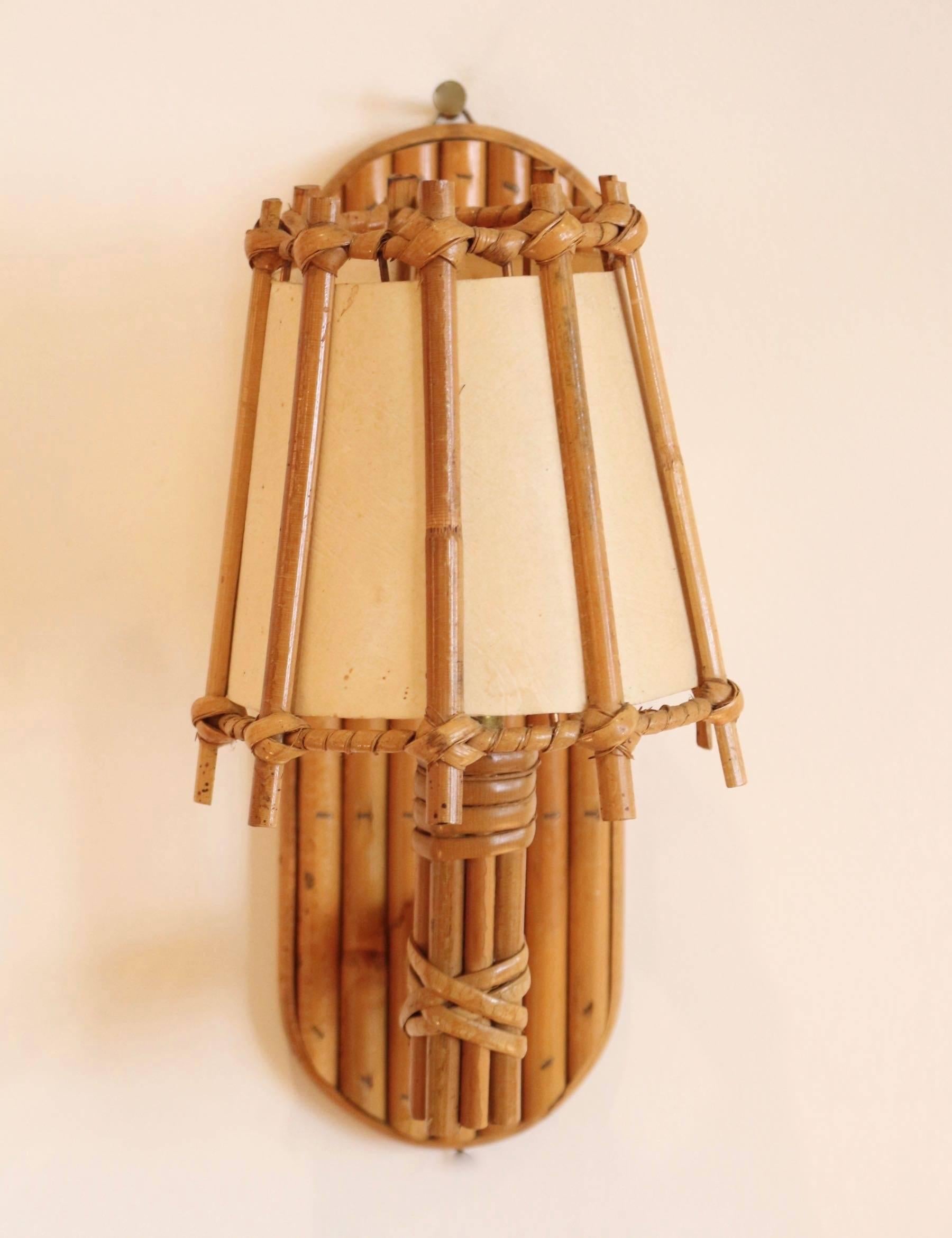 Pair of 1950s sconces attributed to Louis Sognot.
Consisting of assembled rattan rods.
On lighted arm decorated with a rattan lampshade doubled with a white cotton lampshade.
         