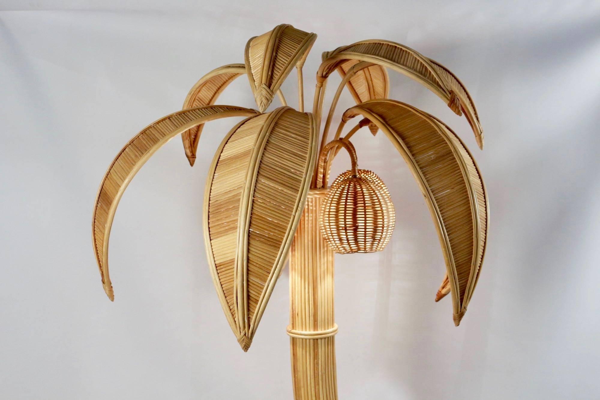 1970s large rattan coconut tree floor lamp.

The trunk, softly wavy is made of bamboo stems.
Three lampshades in shape of coconut conceal the bulbs.