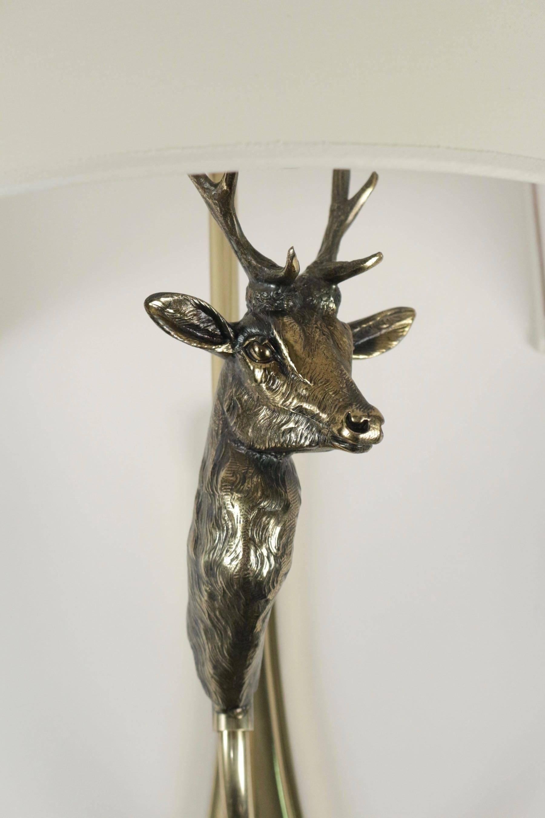1960s Maison Honoré pair of bronze sconce with deer head. 

The both brass arms are adorned with a deer bronze head. 
Hand made lampshades of off-white cotton granteed to the originals. 

Two bulbs per sconces.