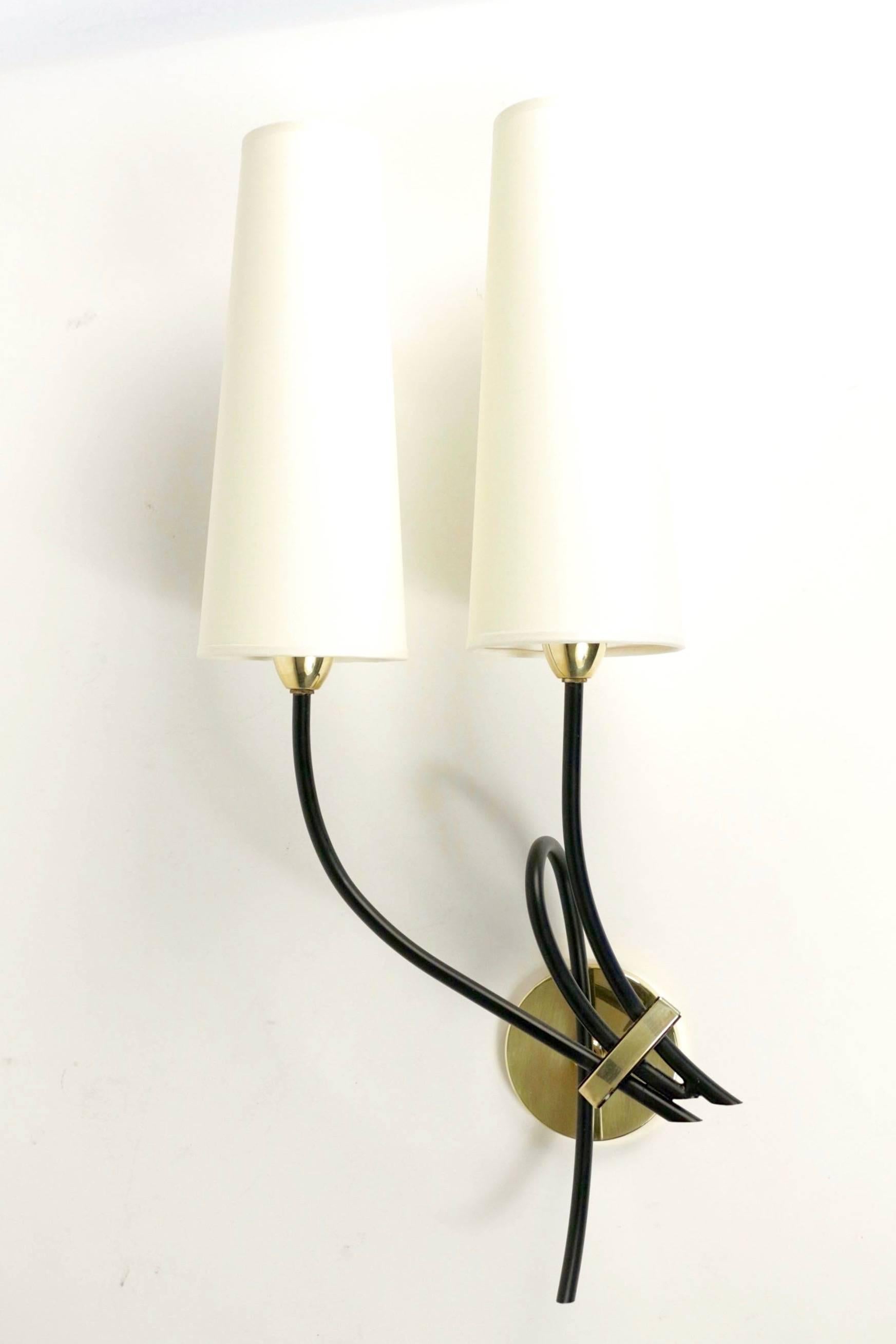 1950s large pair of Arlus sconces.

Each sconce is composed by three curved and black lacquered stems mounted on a round brass back plat, hold together by a piece of brass.

Two stems are ended with two handmade lampshades in withe ivory cotton,