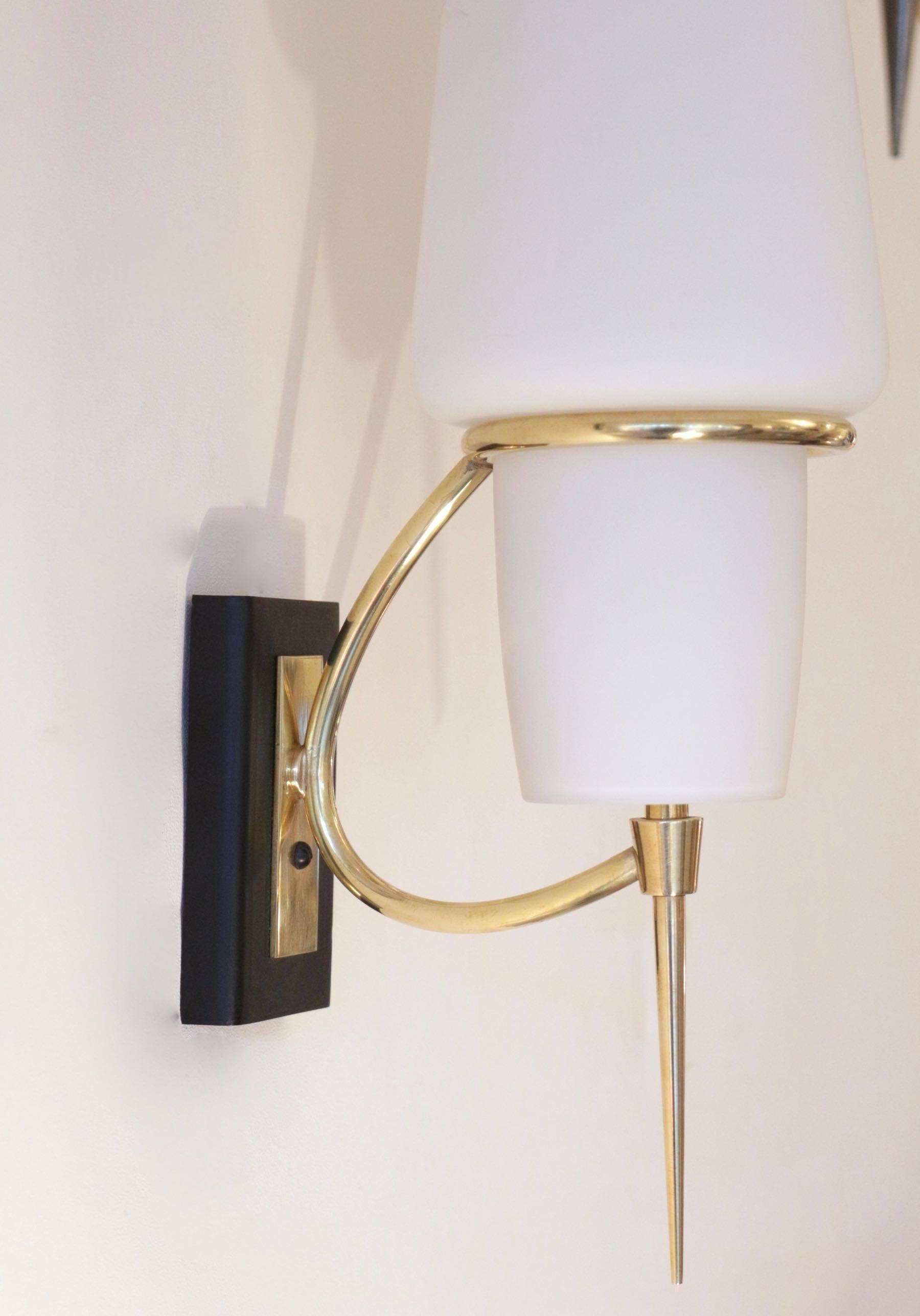 1950s Maison Lunel sconces.

Black lacquered back plate highlighted with a brass rectangular plate.
A brass buckle ended with a trapered brass stem, supports a withe opaline glass lampshade.

One bulb per sconce.
   