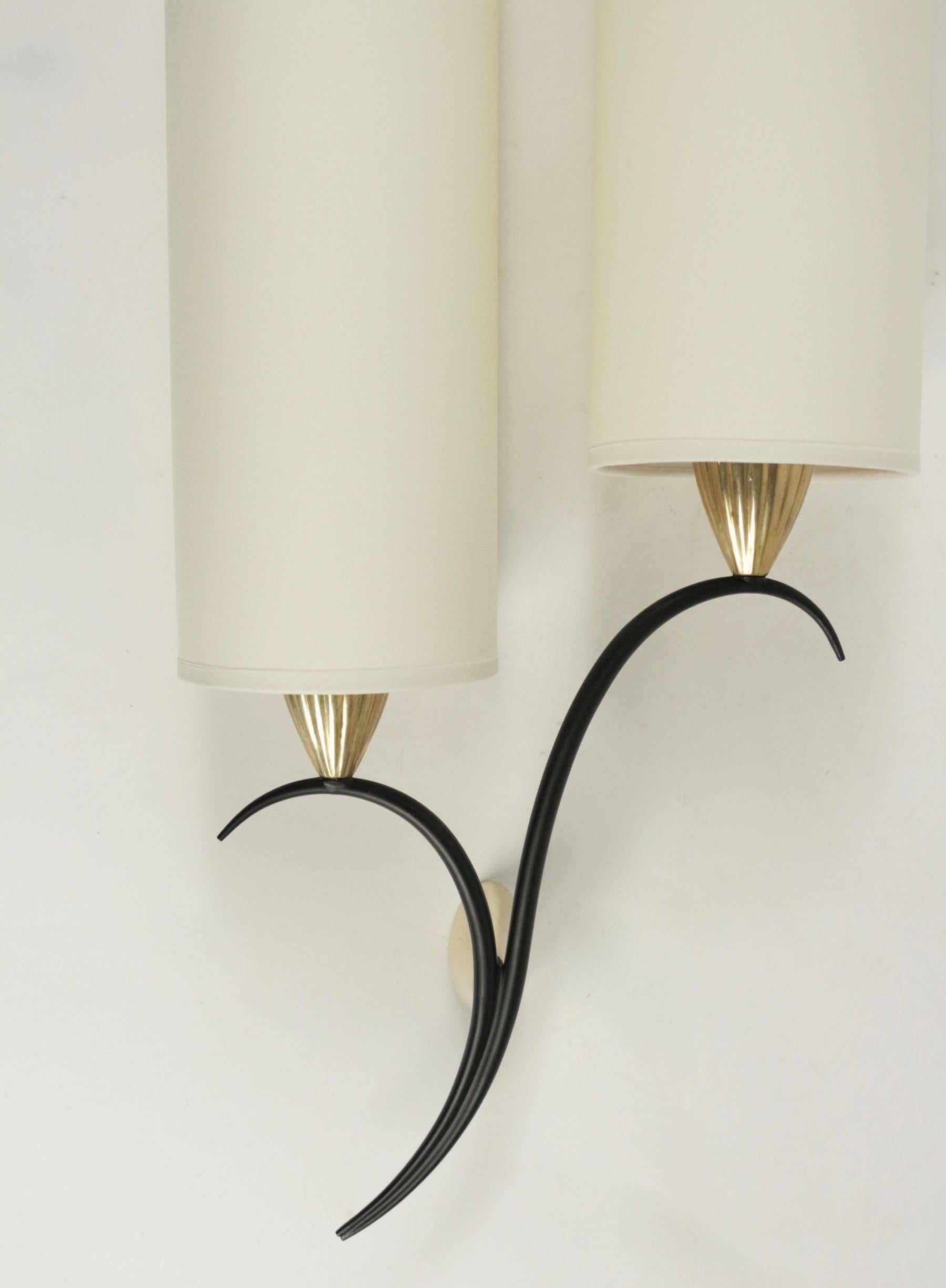 1950s pair of Arlus sconces.

The sconces are composed by two curved black lacquered arms.
The wall mounting and the bulbs sockets are made of gilded brass.

Handmade cylindrical lampshades granted to the originals, made of off-white cotton.