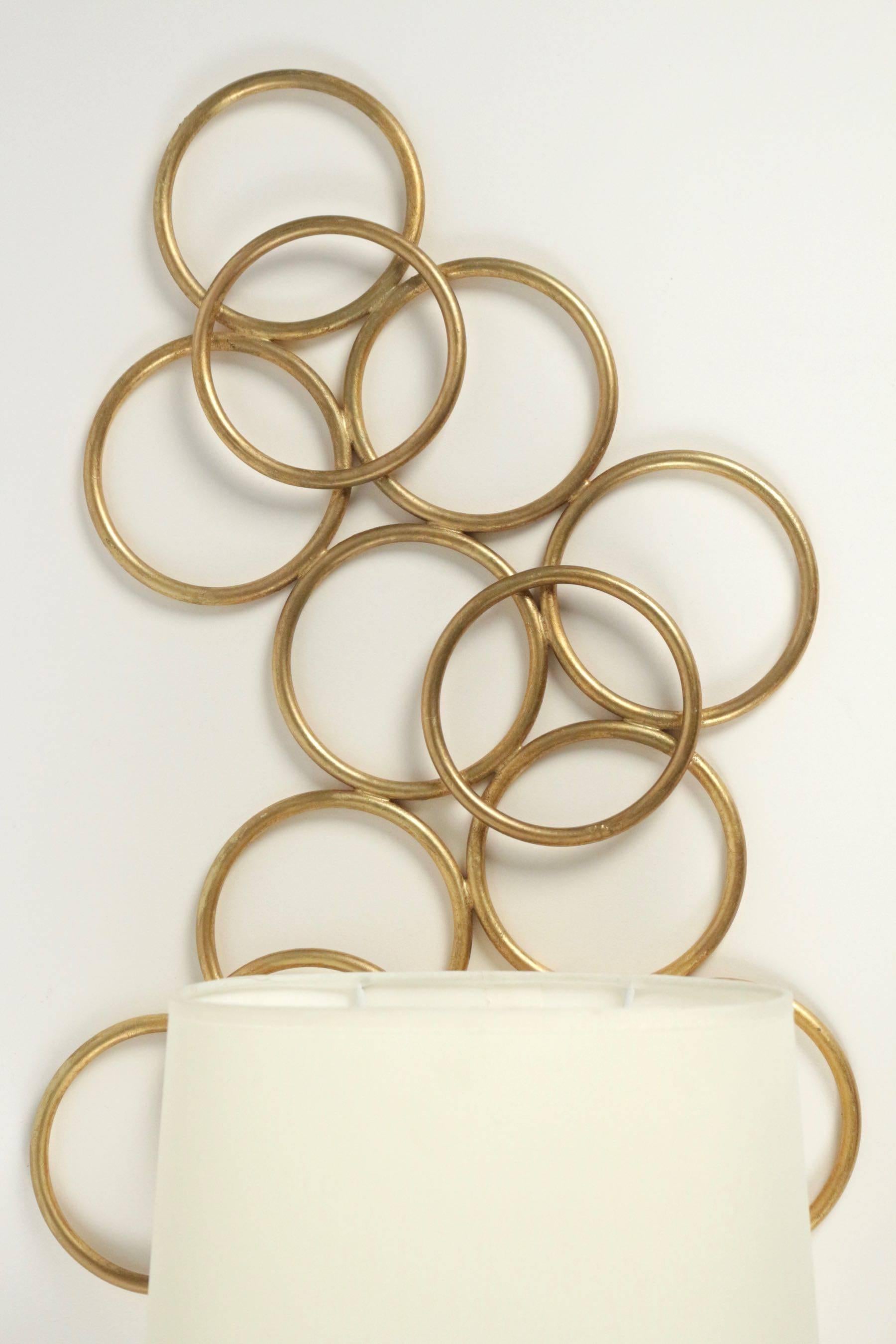 1970s pair of Maison Honore sconces.

Made of intertwined circles, made of gilded metal.
Oval lampshade made of off-white cotton.

One bulb per sconce.