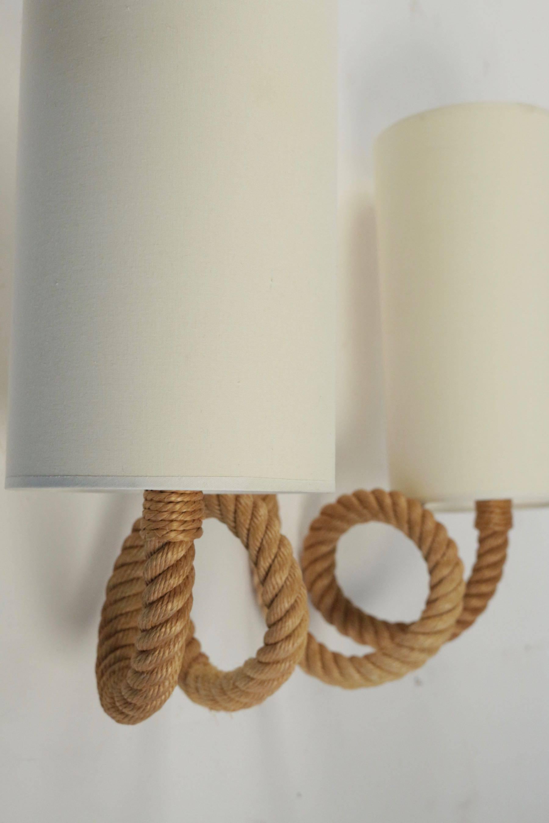 1950s large pair of Audoux and Minet sconces.

Two rope arms are ended with cylindrical lampshades made of off-white cotton. 
The arms form a rope buckle which allow to hang up the sconces to the wall.
