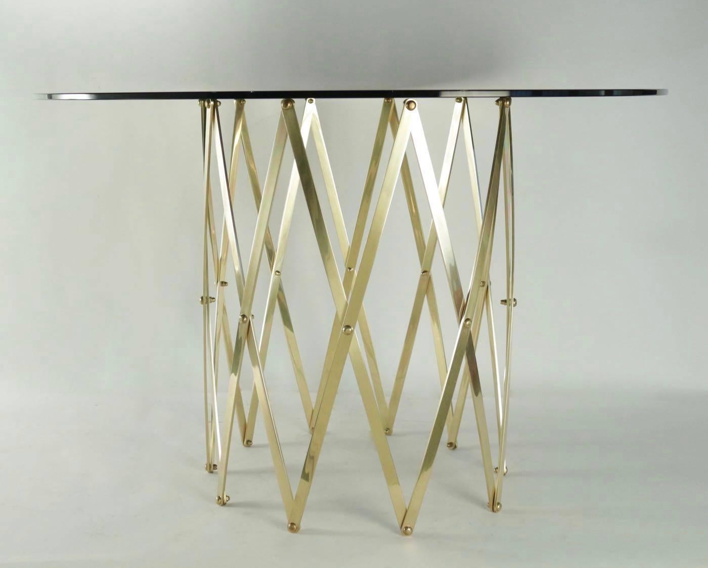 1960s Maison Honoré Extensible Brass Cross Brace Table.

The table base is composed by twenty brass stems which form cross brace motif.
The diameter and the height of the table base is adjustable, nice and clever system.
Round table plate of black