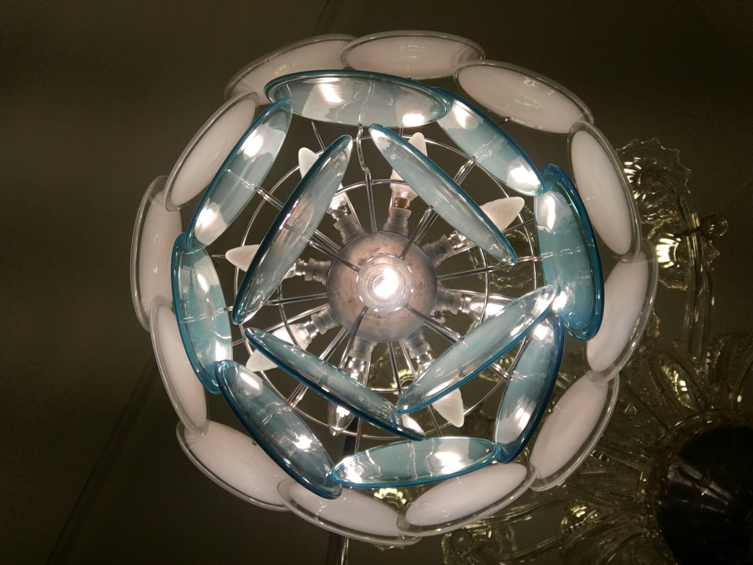The 24 white and 
turquoise discs of precious Murano glass are arranged on three levels. Nine lights. Height without chain 40 cm.