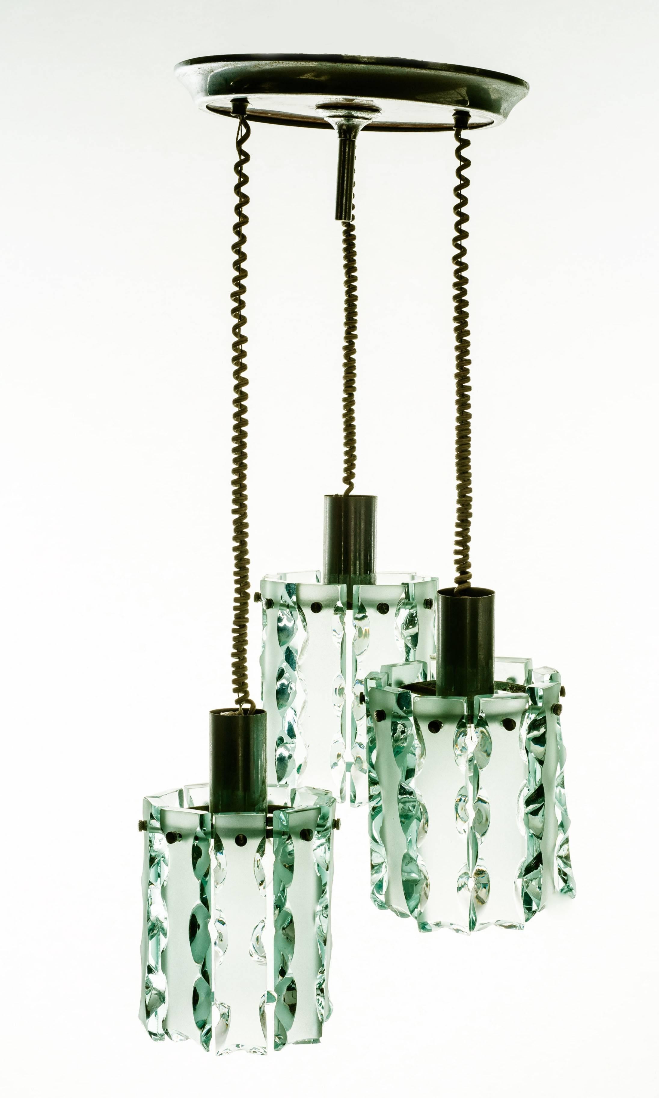 Elegante trio di luci. 24 lame di vetro con bordi scheggiati in colore Verde Nilo. I bicchieri di ogni gruppo sono alti 20 cm e hanno un diametro di 15 cm.