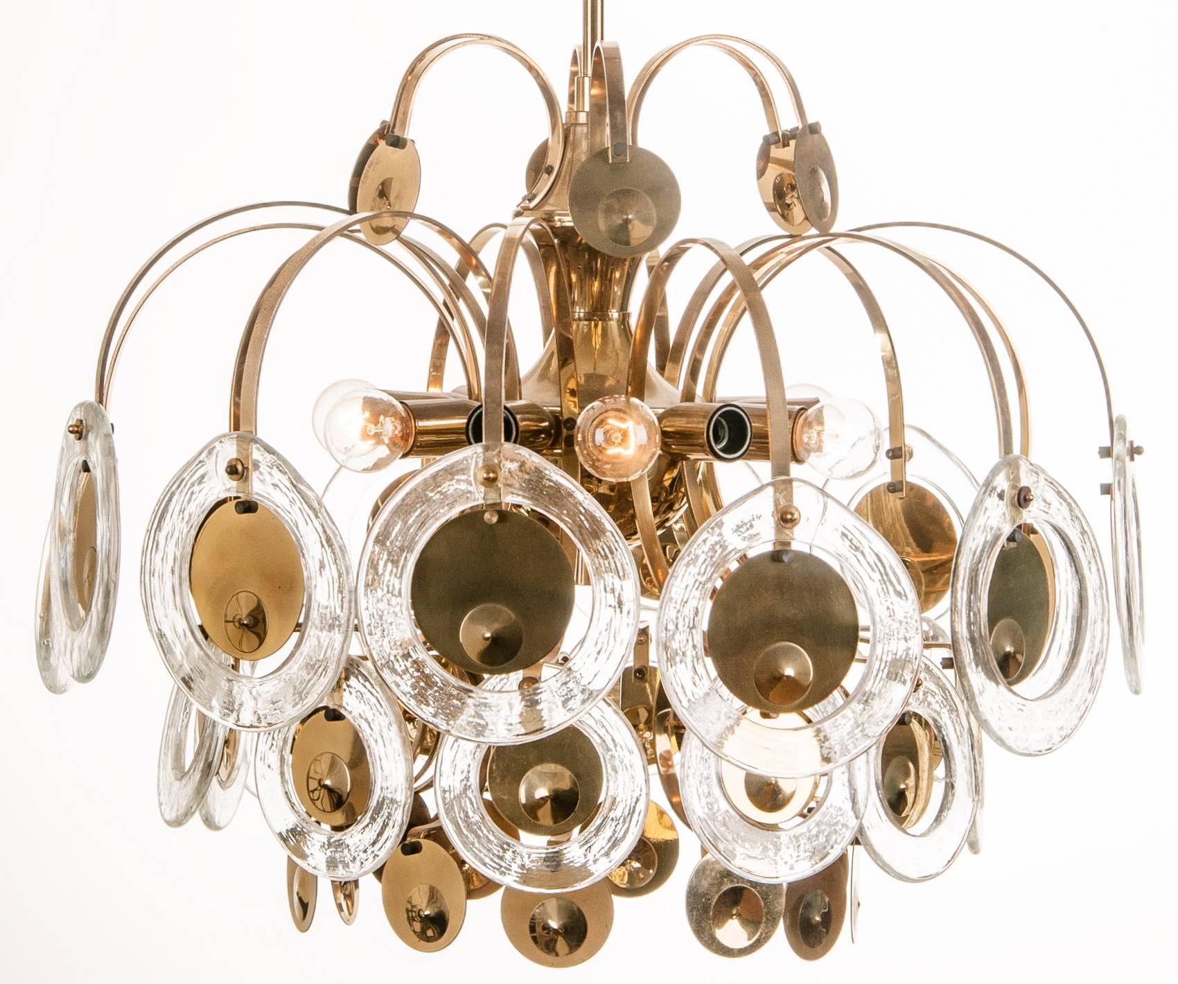 Rare chandelier by Gaetano Sciolari. It is made by dozens of blown glass rings that surround the brass circles. Amazing lighting effects.
Available a pair.
