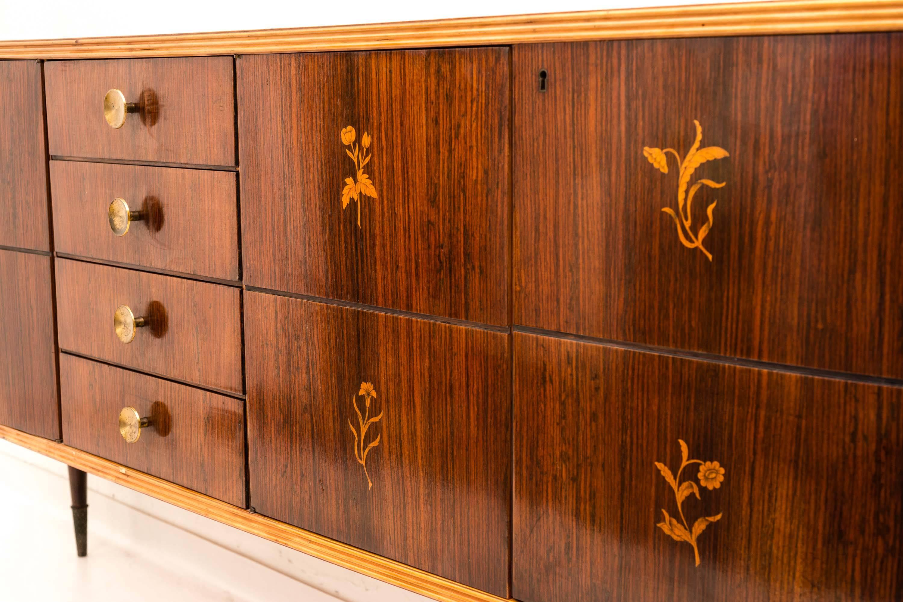 Unique and unusual sideboard designed by Pier Luigi Colli. Features finely carved and painted legs decorated with acanthus leaves.
Decorated front doors with nature motifs with the use of precious woods centered by four drawers with brass knobs.