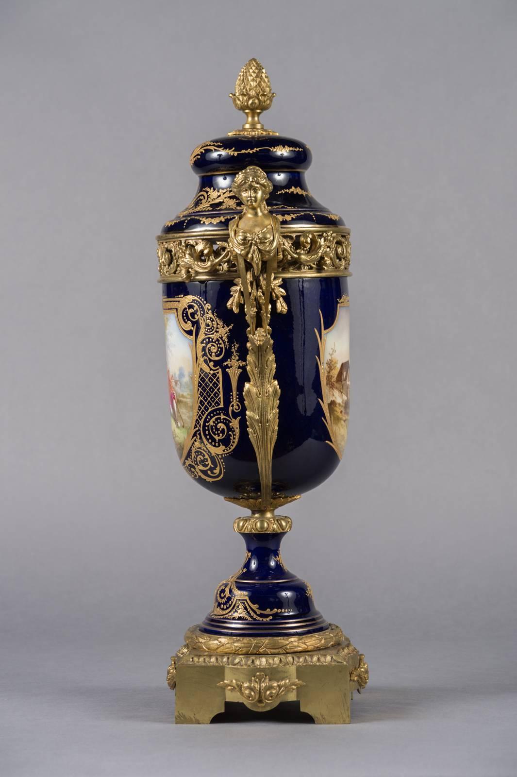 A magnificent and large pair of 19th century French Sevres cobalt blue Porcelain gilt bronze mounted covered urns. Each panel is beautifully hand painted with love scenes and the reverse panels with landscapes. and further adorned with raised gold