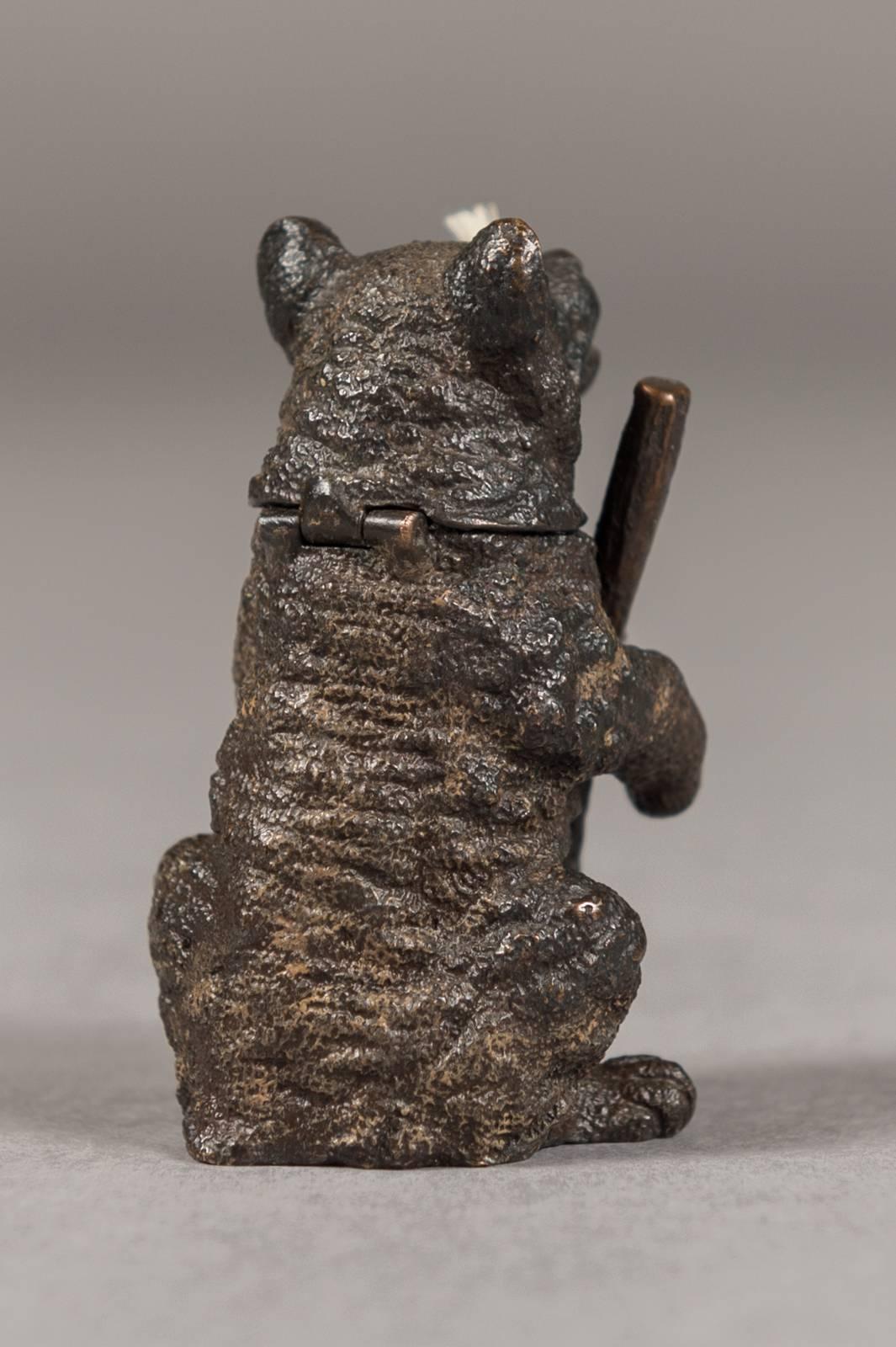 An Austrian bronze figural cigar lighter modeled as a bear holding a rifle.

Austria, circa 1900.

The wick extends from the cigar in his mouth, head is hinged to accept fuel, marked on bottom 