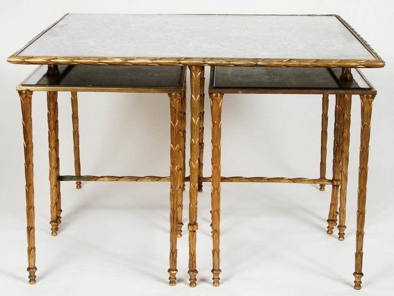 Vintage gilt bronze Maison Baguès coffee table with four nesting tables and tops of silver oxidized mirror. Features stylized leaf decoration. Made in France circa 1950-1970. The tables are in good vintage condition. Items sold