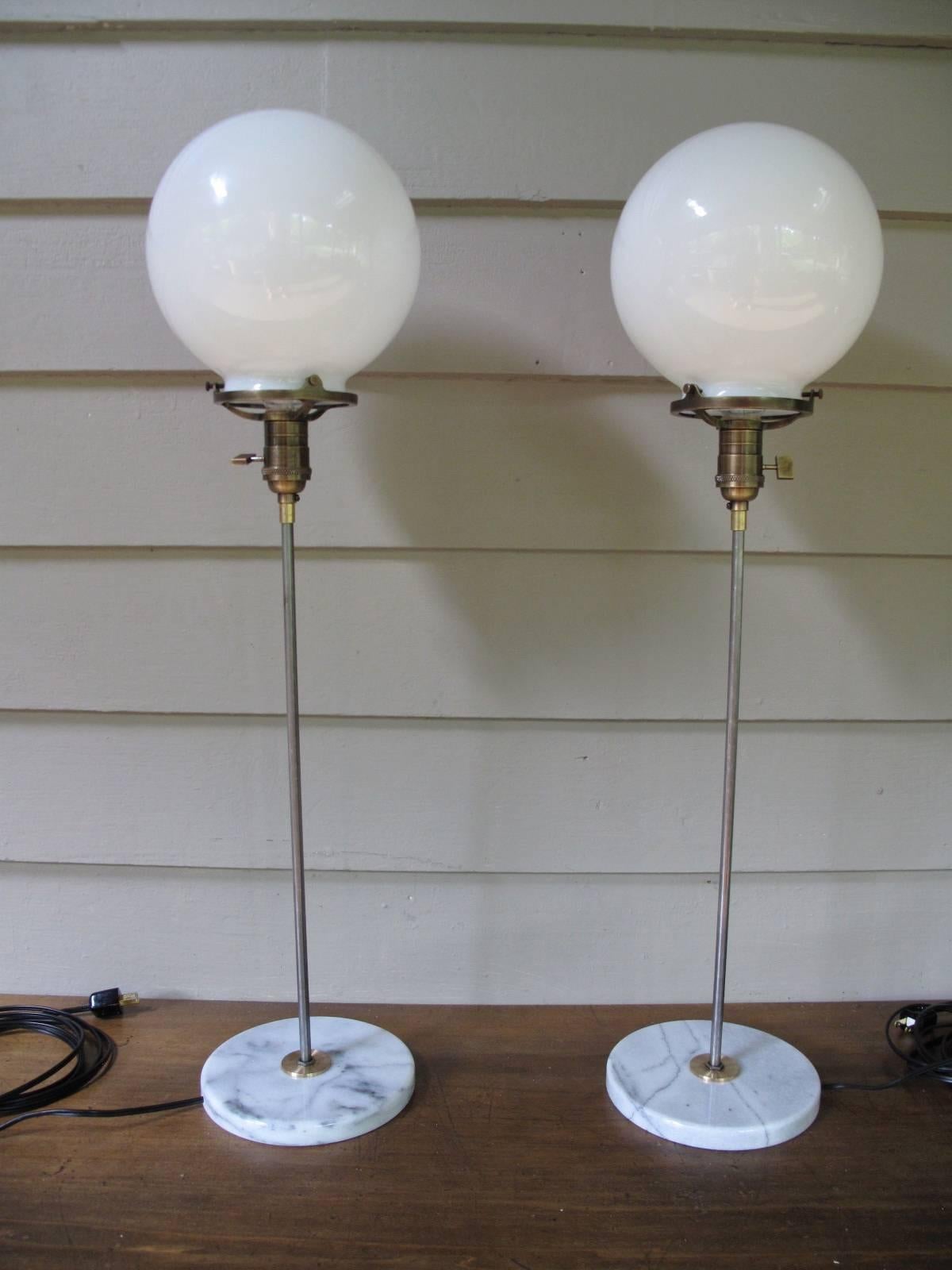 Pair of table lamps, each having round milk glass shades on steel rods. Veined white marble base. 

Globe diameter 8