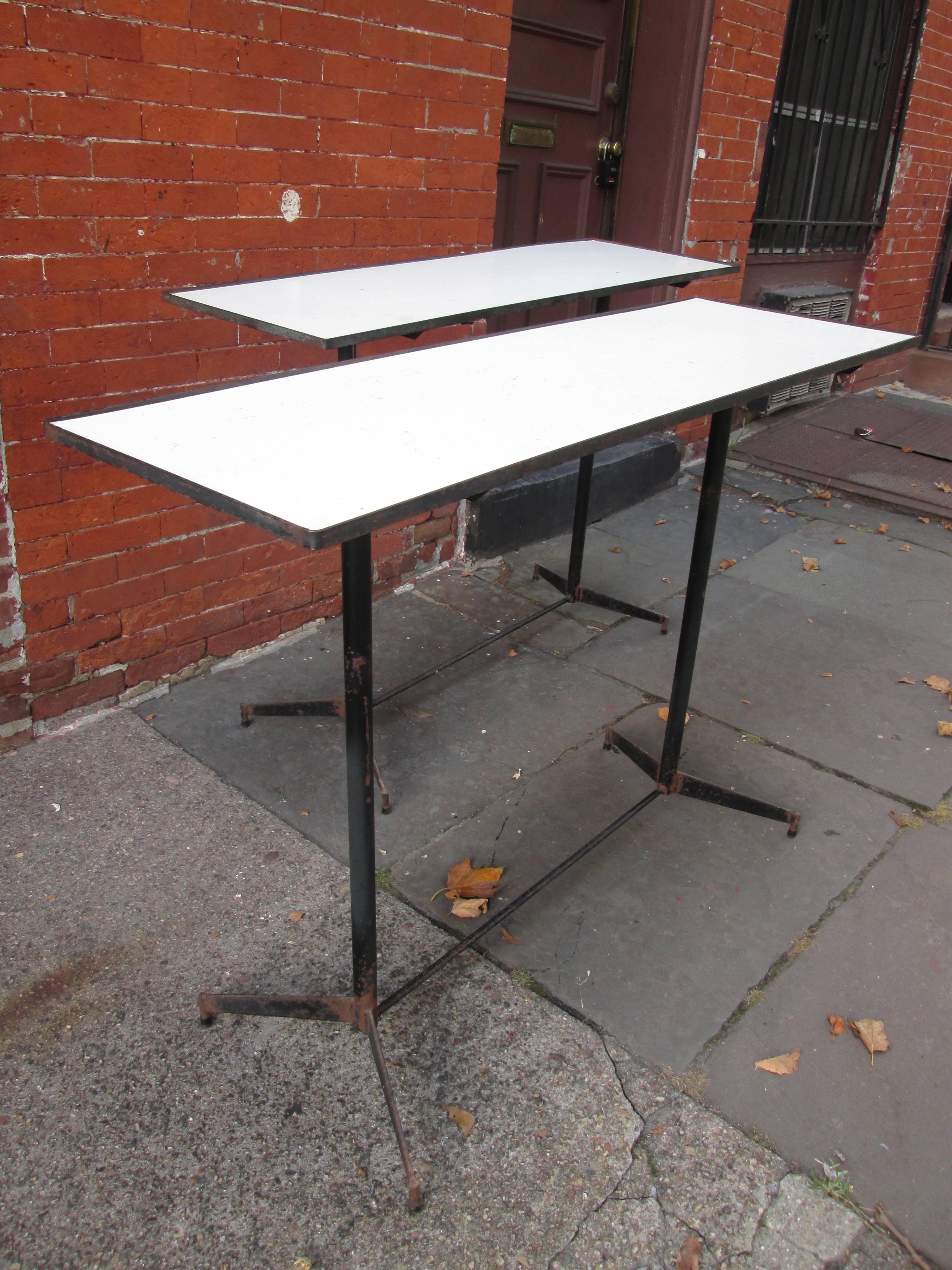 Two rectangular tables with iron frames and composite board surfaces.