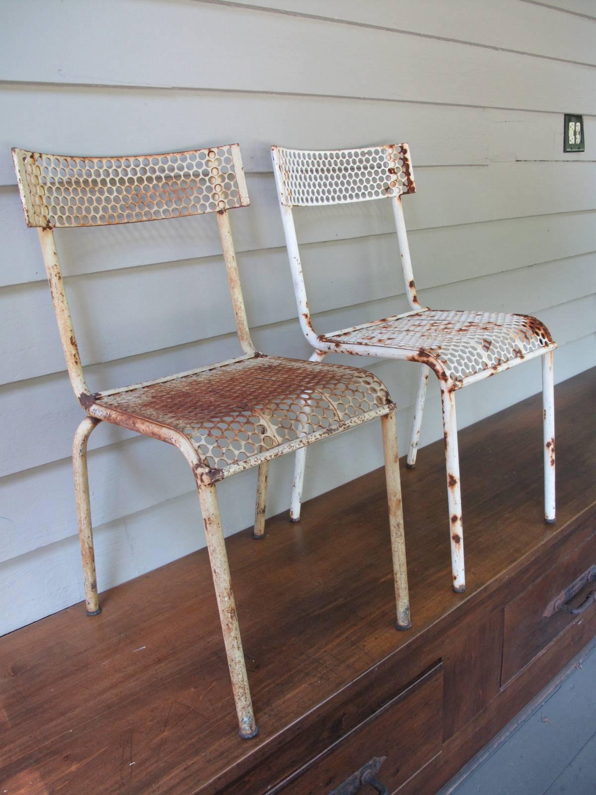 Similar French bistro chairs. Beehive perforated design on backrest and seat. Tubular steel frames. Color varies slightly, one being closer to white and the other ivory.