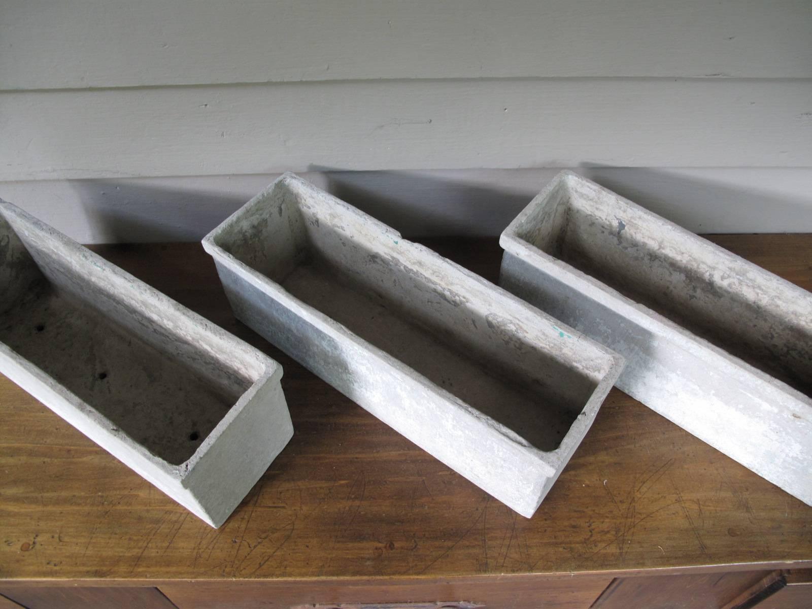 Three fibercrete planters with lip attributed to Swiss designer Willy Guhl. Three drainage holes along bottom of each planter. No apparent makers marks.