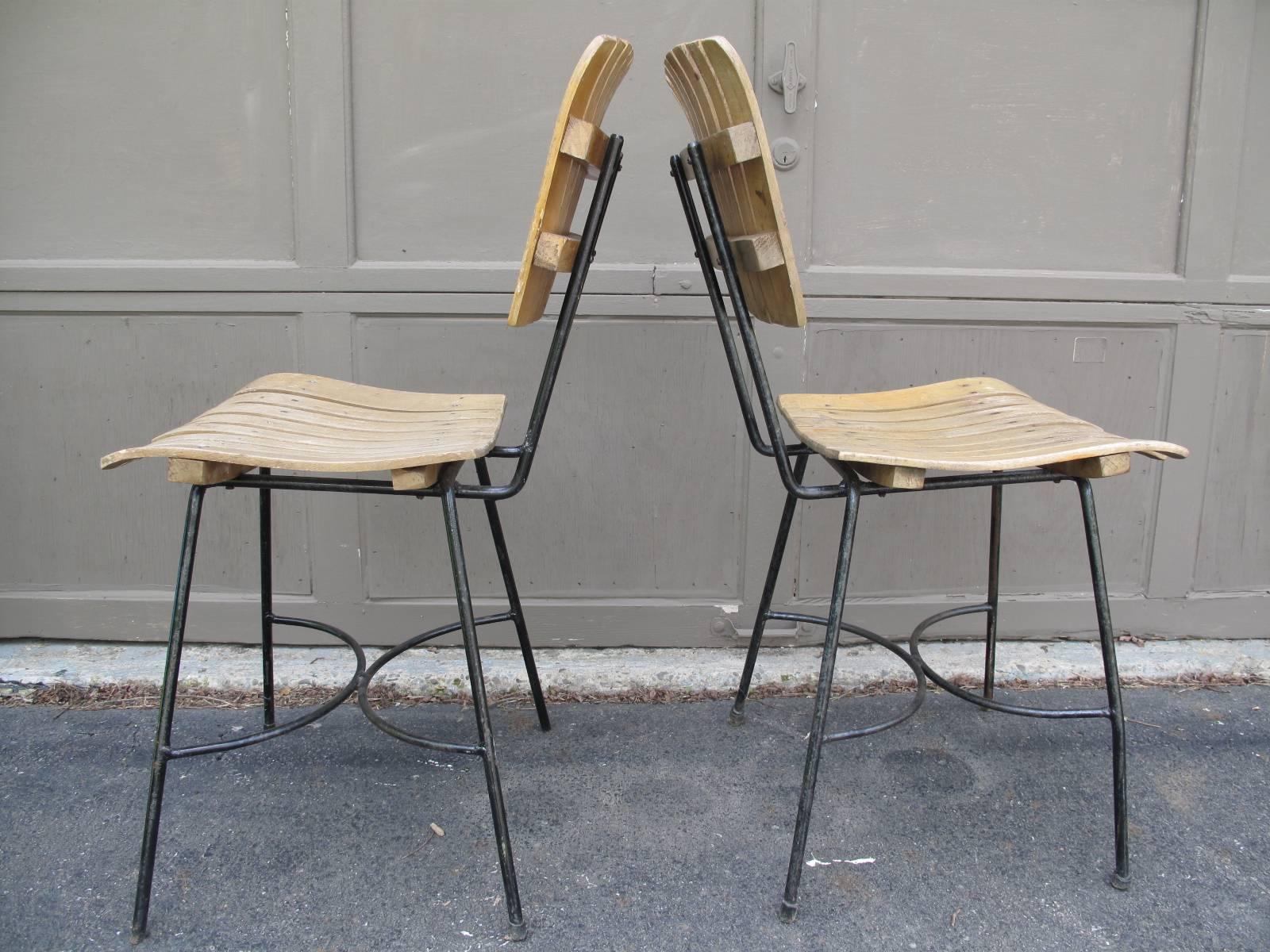 Two iconic Mid-Century iron chairs with slat seats and backs, similar to those by American designer Arthur Umanoff.