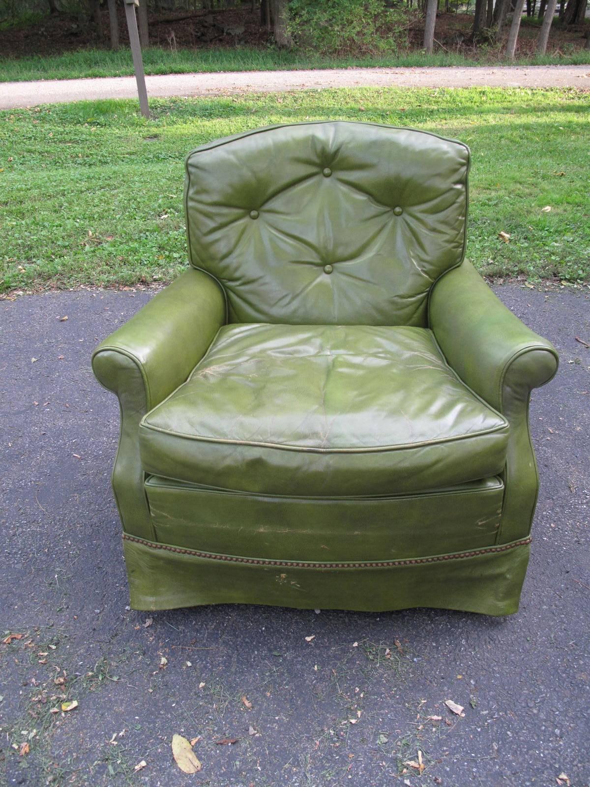 20th century American club chair by Baker Furniture. Tufted green leather. Skirted base with nailhead detail.