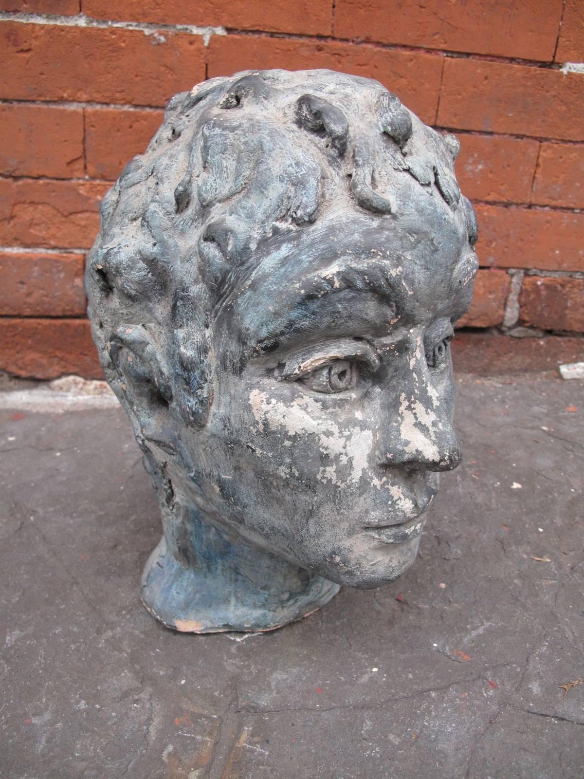 Lifesize clay bust of a young man with detailed curly hair.  