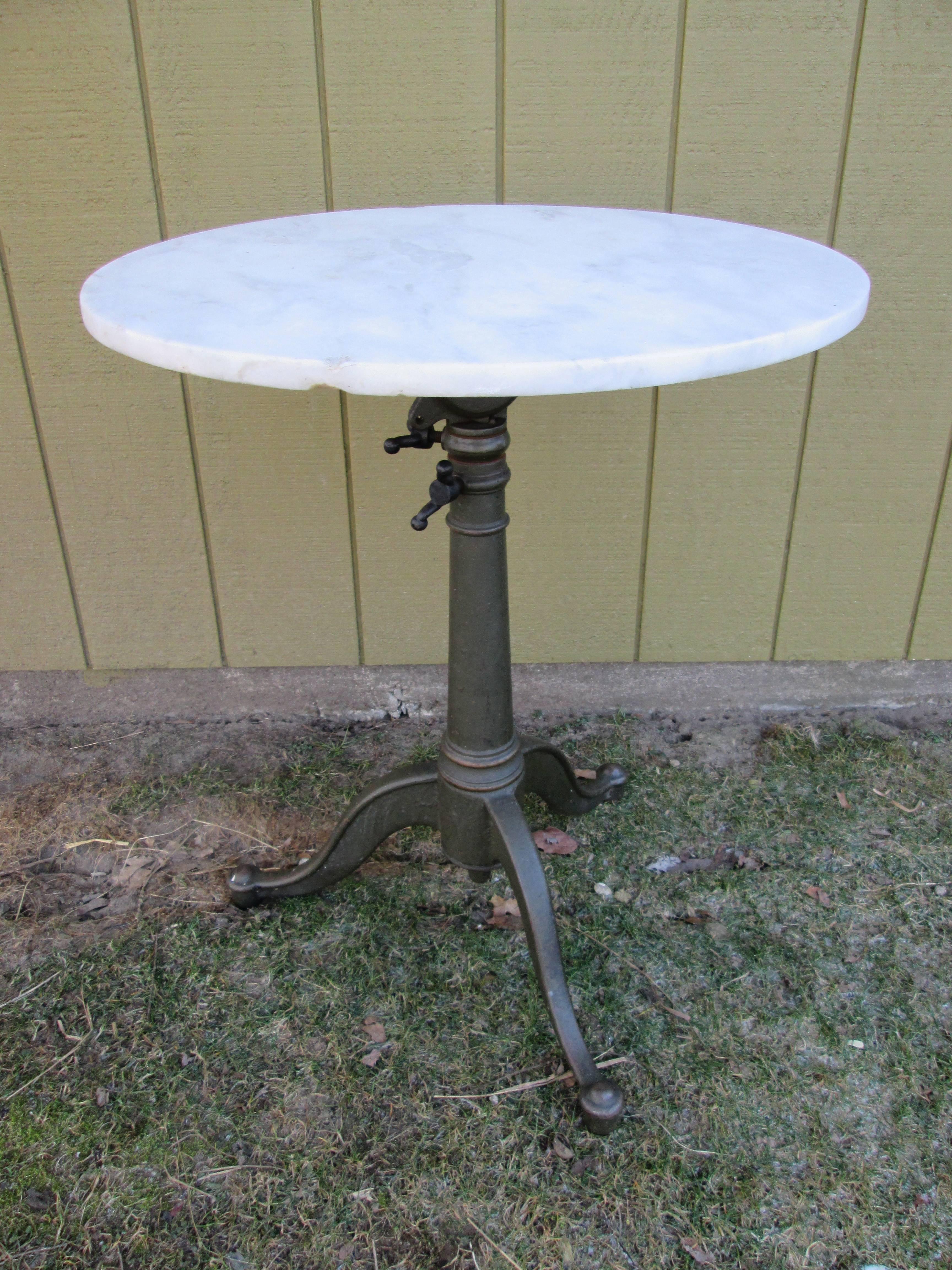 Honed round white marble top. Adjustable drafting table base in original dark paint. 
