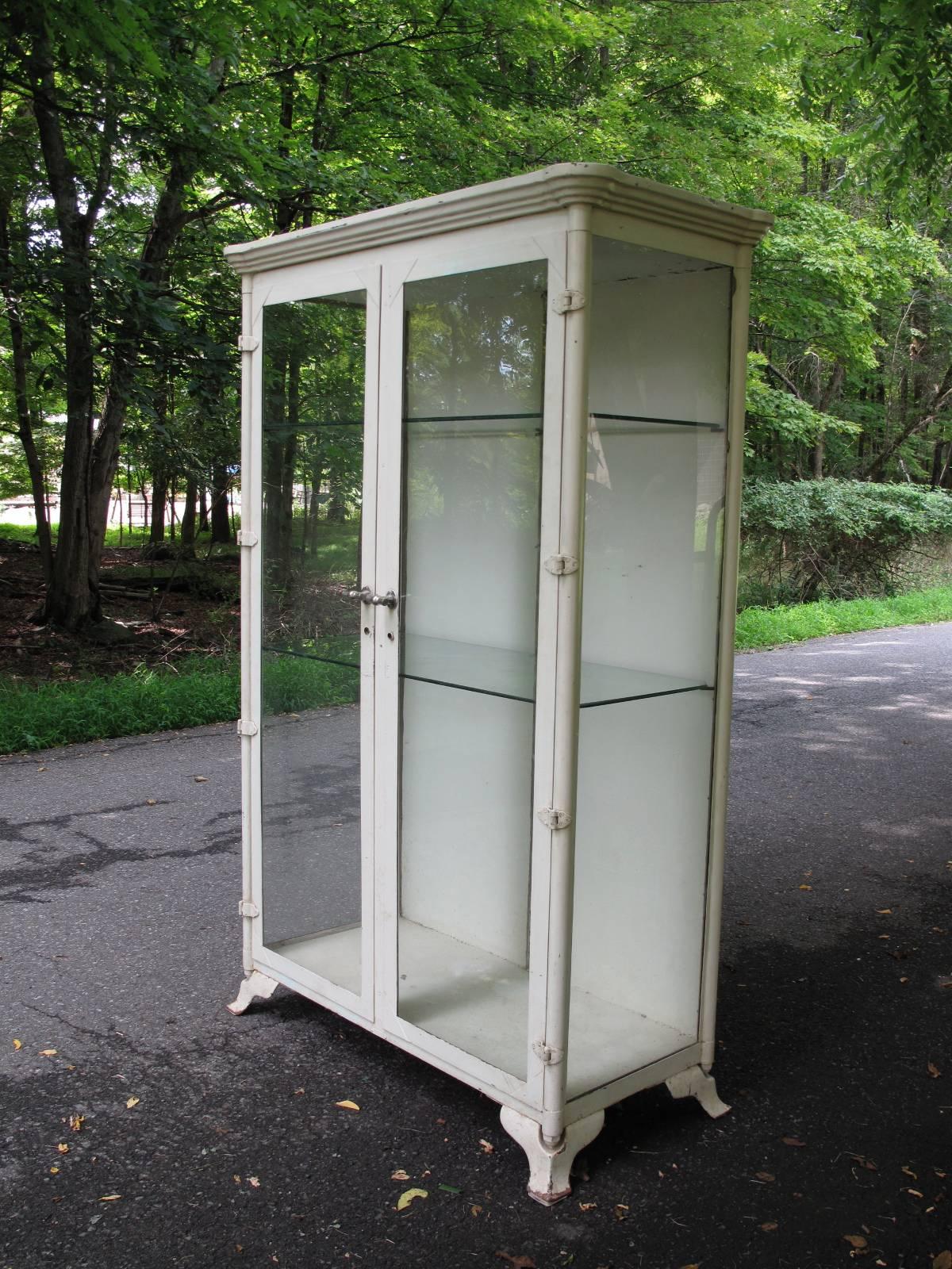 Early 1900s painted iron cabinet with 3/4 glass profile. Original nickel handles with interior latch. Patented July 30th, 1903.