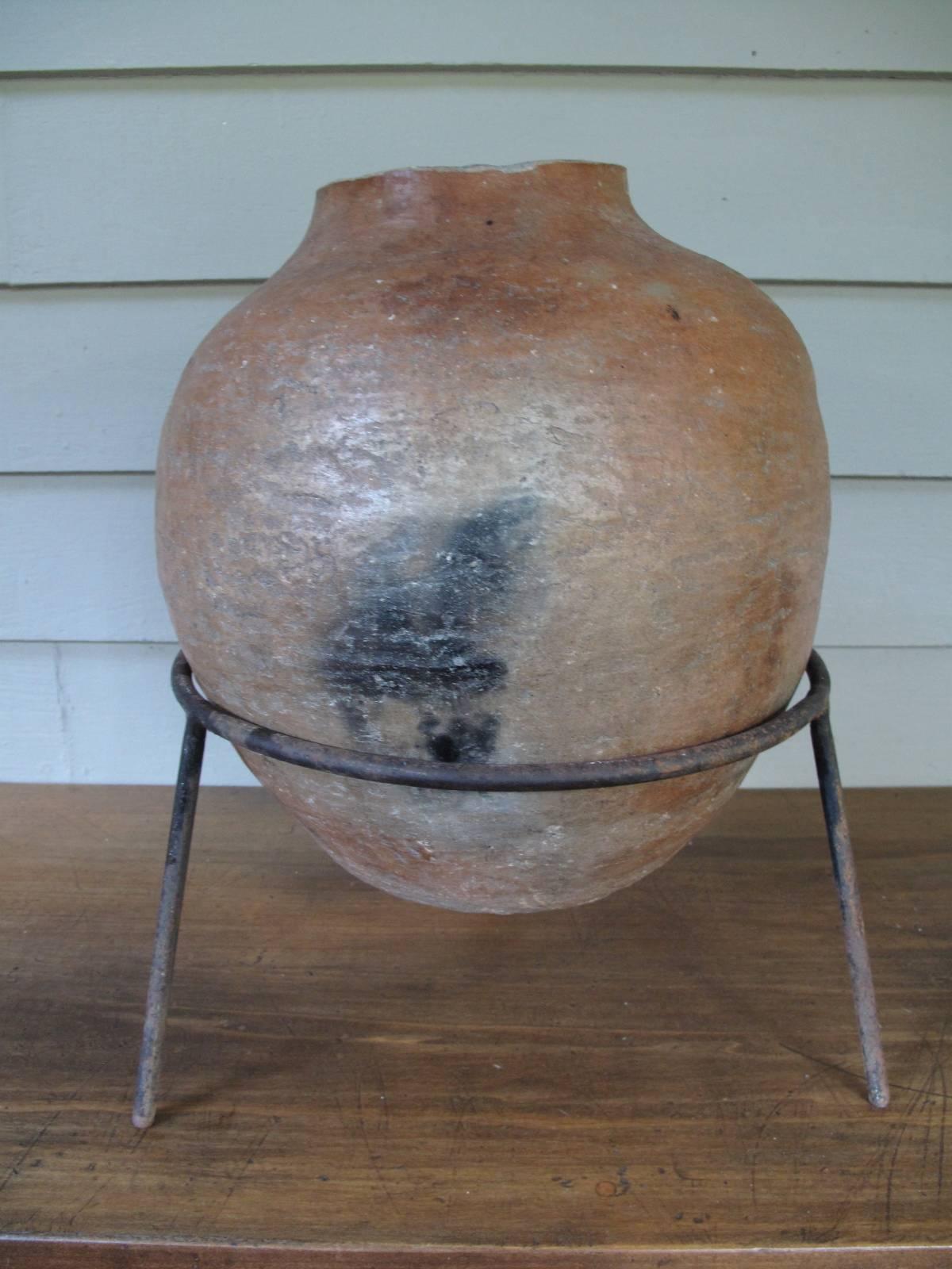 Handmade wide mouth terra cotta vase. Sits in round iron stand with three legs.