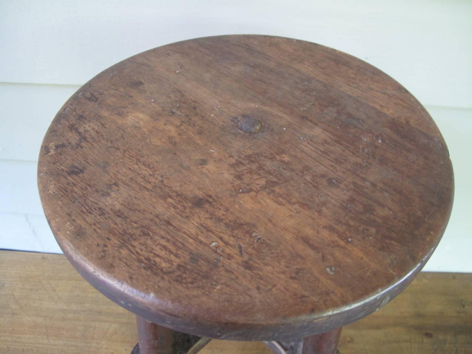 1900s American stool. Unique form. Legs are supported by a wood cross brace and a single metal rod.