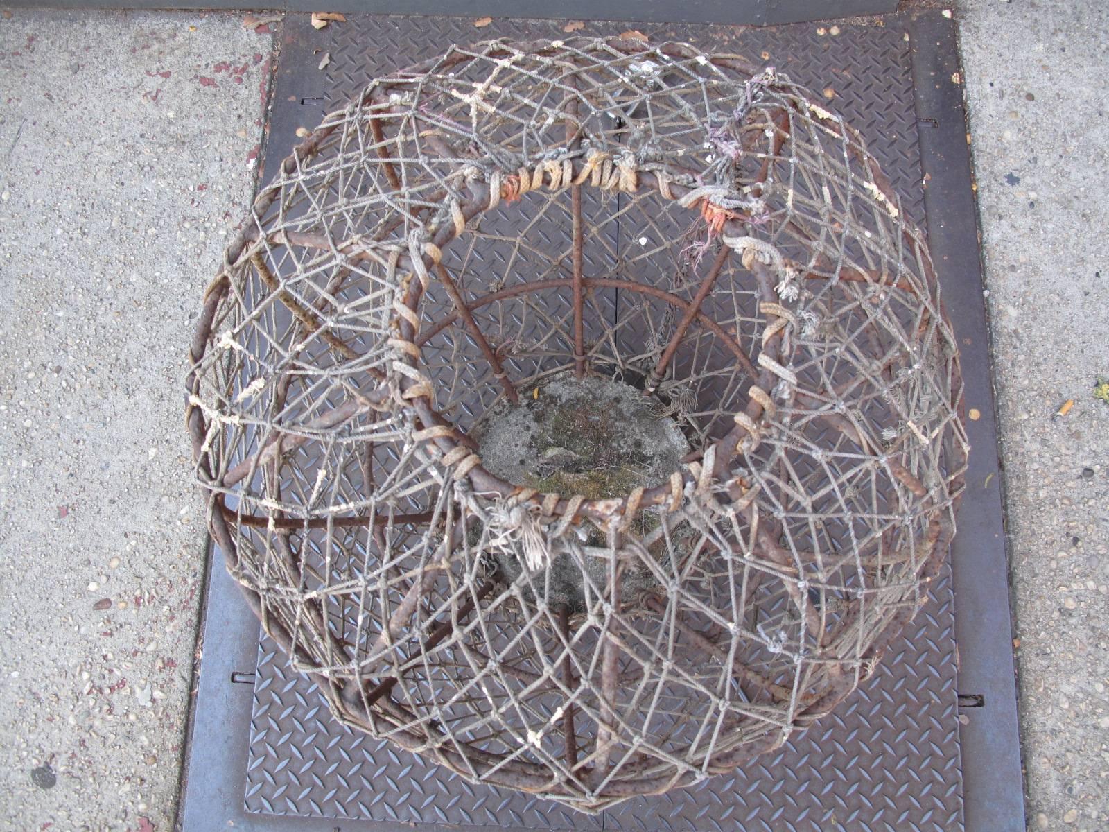 Massive weighted iron crab pot. Hand-knotted using a variety of ropes. Concrete base.