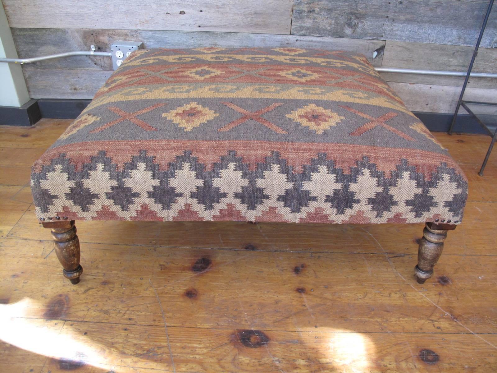 Massive ottoman upholstered in flat-weave Kilim. Turned legs.