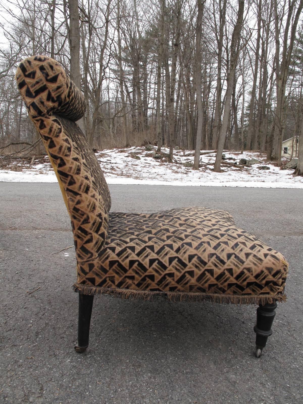 Petite armless chair in distressed cut velvet. Petite scroll back. Elegant turned and ebonized legs on small brass casters. Fringe detail along bottom edge.