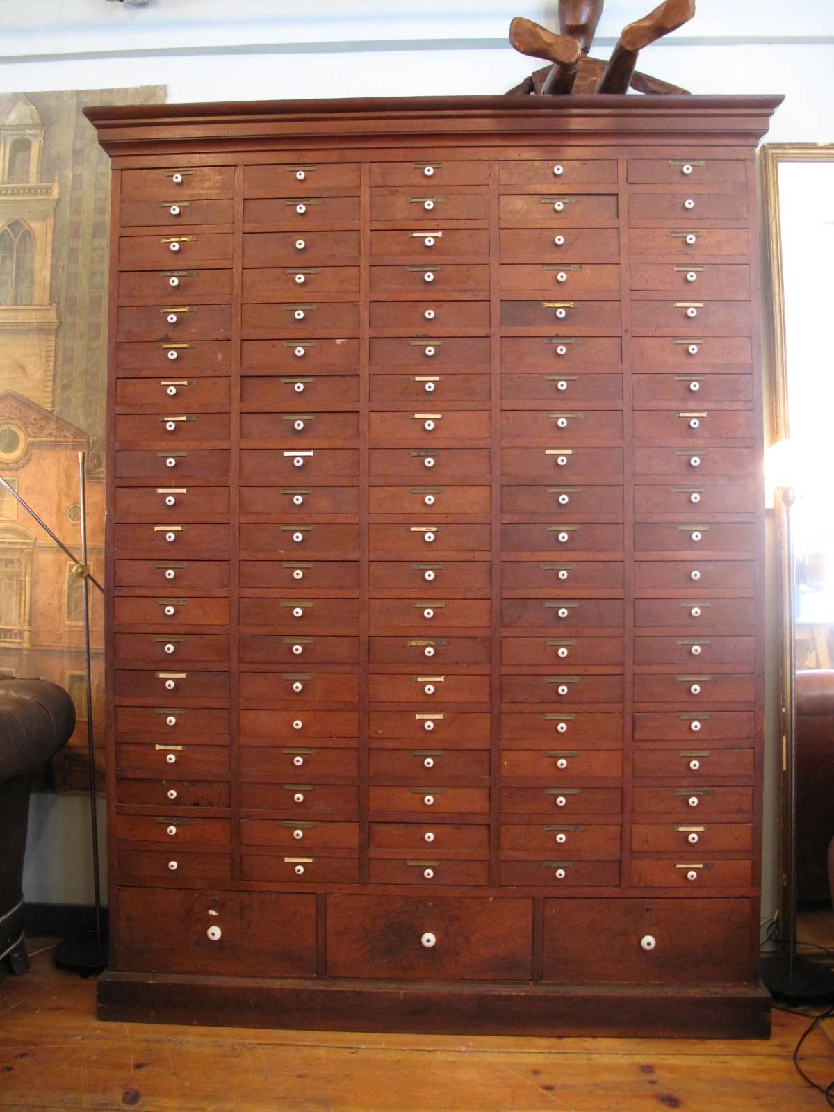 Late 19th century apothecary cabinet with original brass label holders and porcelain pulls. Having three larger lower drawers and 100 small drawers.
