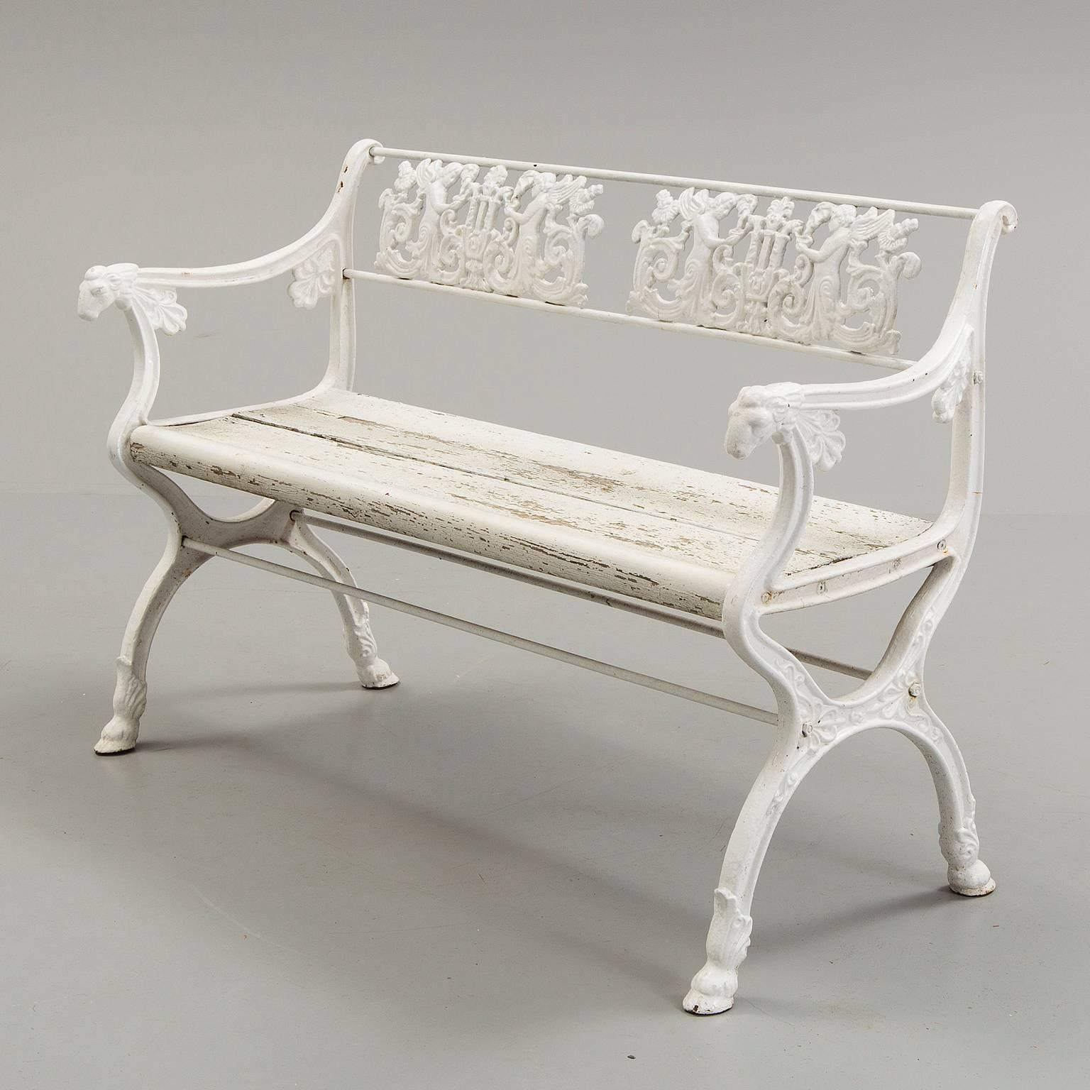 A charming garden bench attributable to  reknown Prussian architect, Karl Friedrich Schinkel, in cast iron with angels in relief along back rail, rams heads on armrest, wooden-plank seat, and resting on trestle base with cloven hoof feet, Germany,