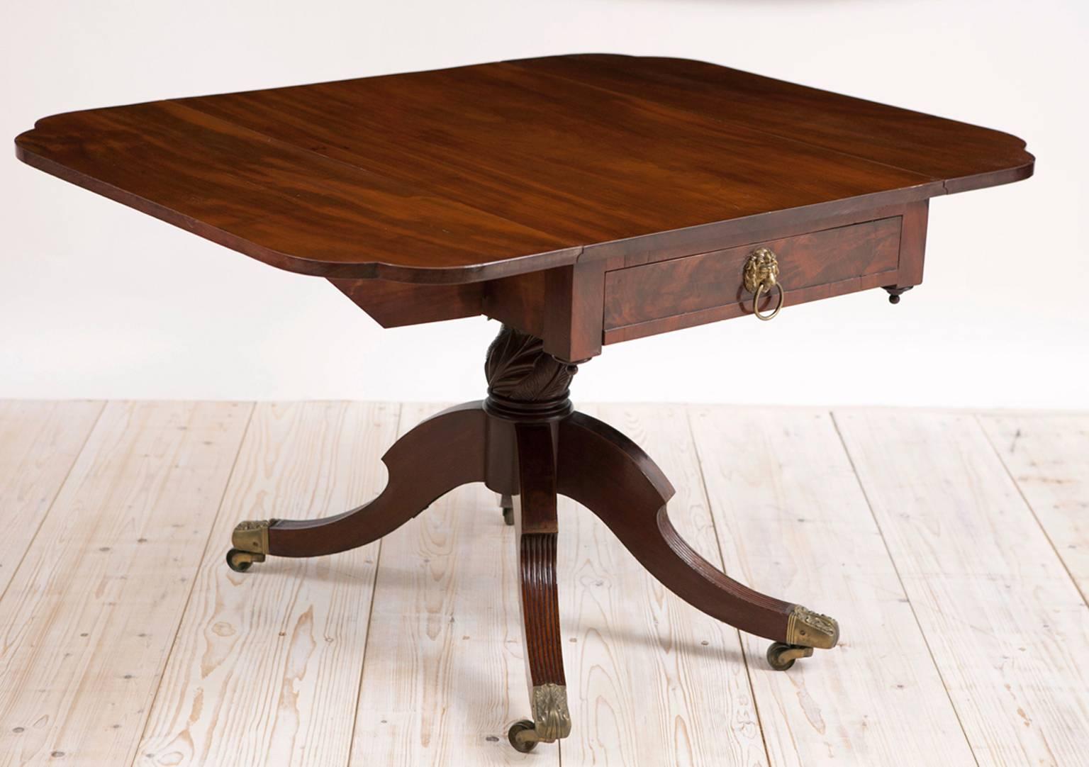 American Federal drop-leaf breakfast or library table with reeded saber legs on baluster pedestal, D-form drop leaves, original brass lion-pull and ring on drawers, and hairy paw Duncan Phyfe-type brass casters. Offers one deep drawer, circa