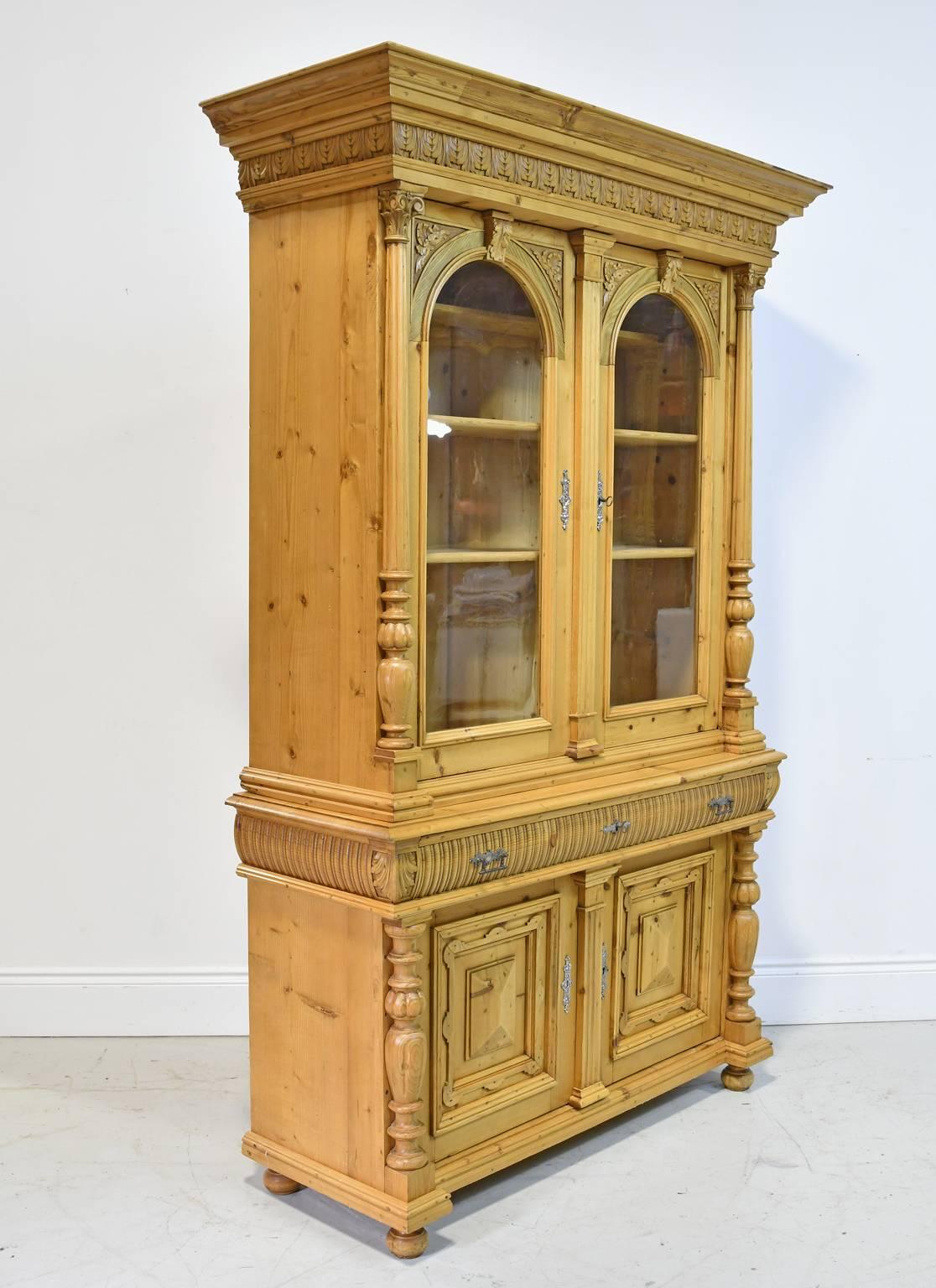 From Sudetenland or present-day Czech Republic, an exceptionally handsome and well-crafted pine bookcase or cupboard with beautifully articulated carvings. Offers carved, arched and glazed upper cabinet doors over two convex and fluted drawers, with