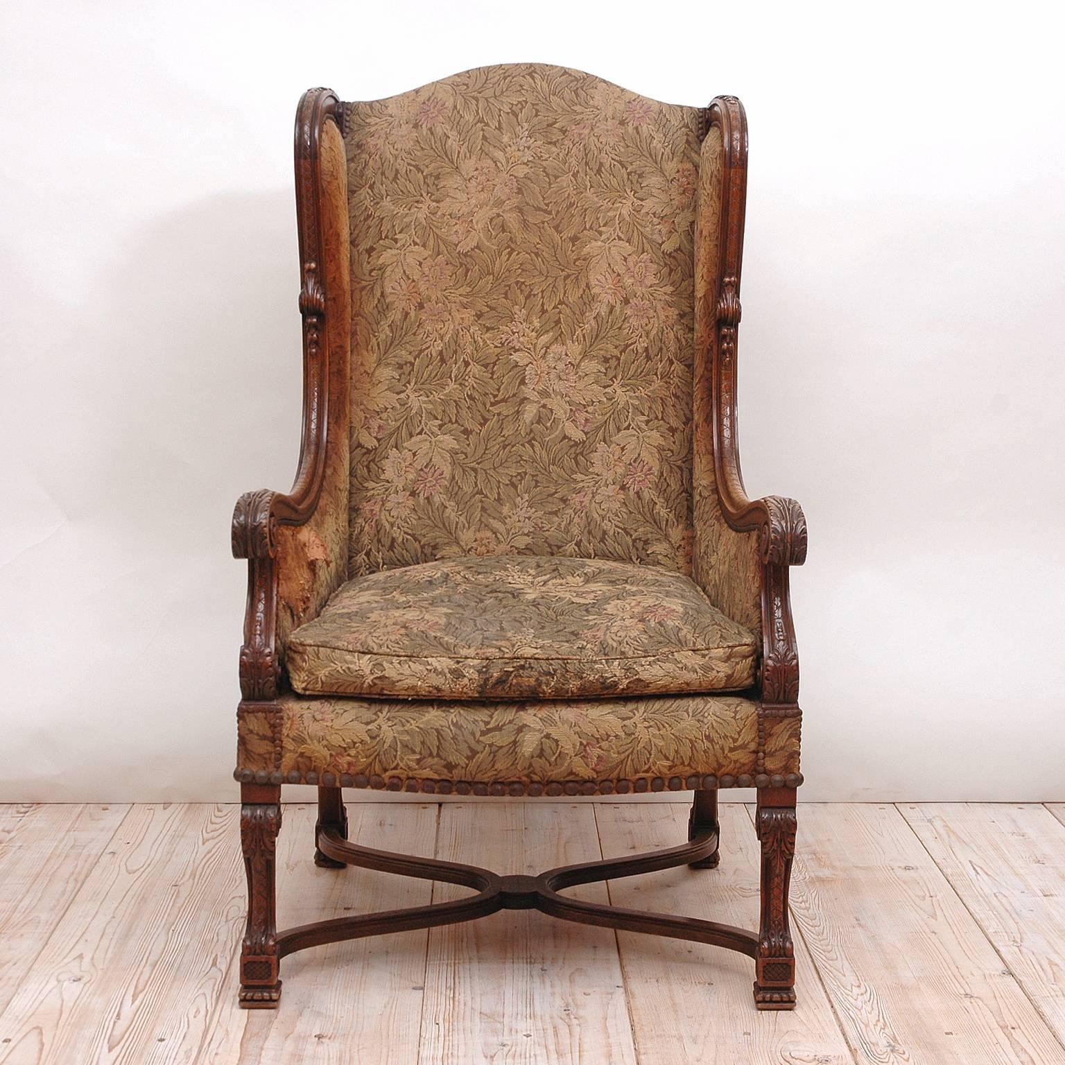 A handsome Renaissance style wingback chair with nicely carved hardwood frame, upholstered back and loose upholstered seat from the Belle Époque. Features carved scrolled arms with acanthus leaves, carved 