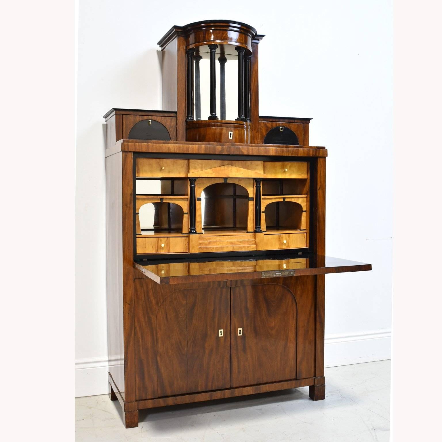 A handsome Swedish Karl Johan Empire Secretary a style better known throughout most of Europe in 1820 as Biedermeier. In mahogany with birch interior and ebonized details. Top gallery consists of three drawers and mirrored colonnade opening to