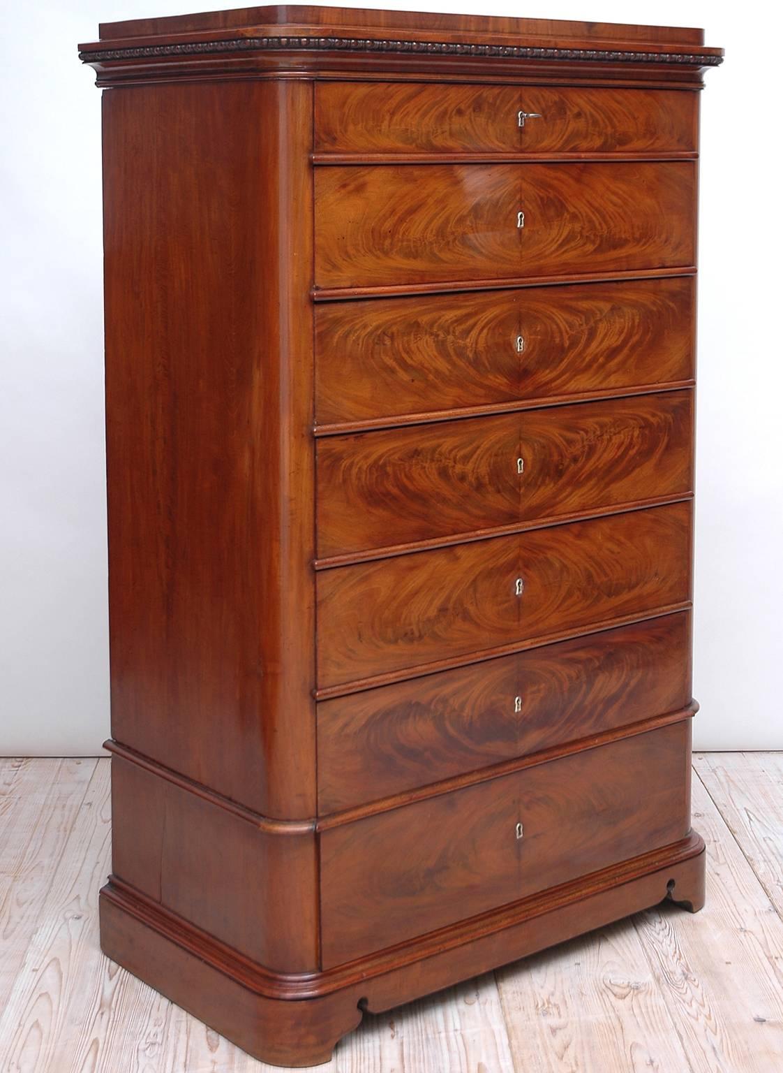 A Biedermeier or Christian VIII semainier or tall chest with seven drawers in mahogany, with bookmatched crotch-mahogany veneer on drawer fronts, pedestal top and plinth base, Denmark, circa 1840.
Offers all original brass key escutcheon plates and